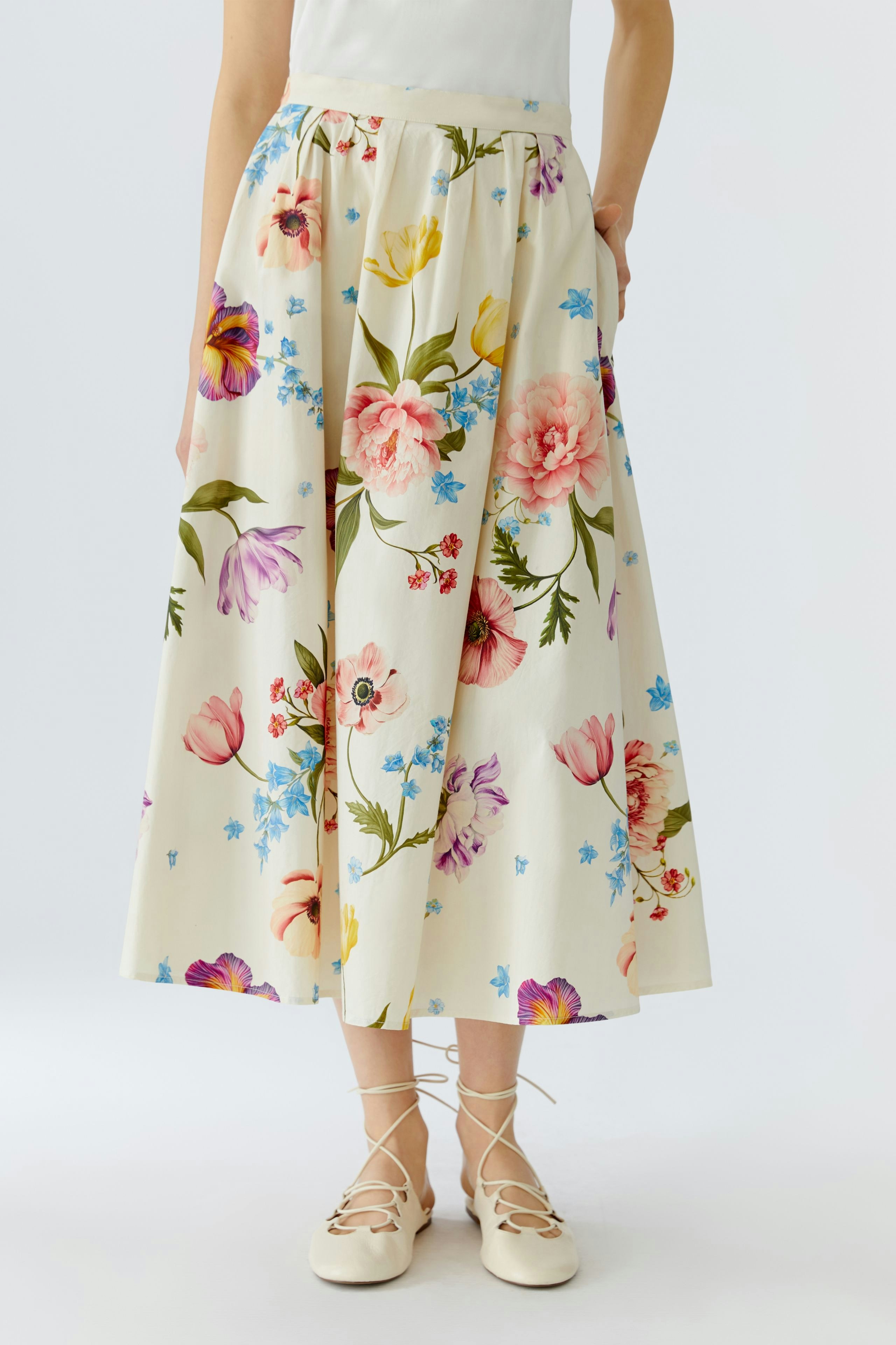 Floral midirock: Woman in a flowy skirt with colorful flowers, paired with a simple top.