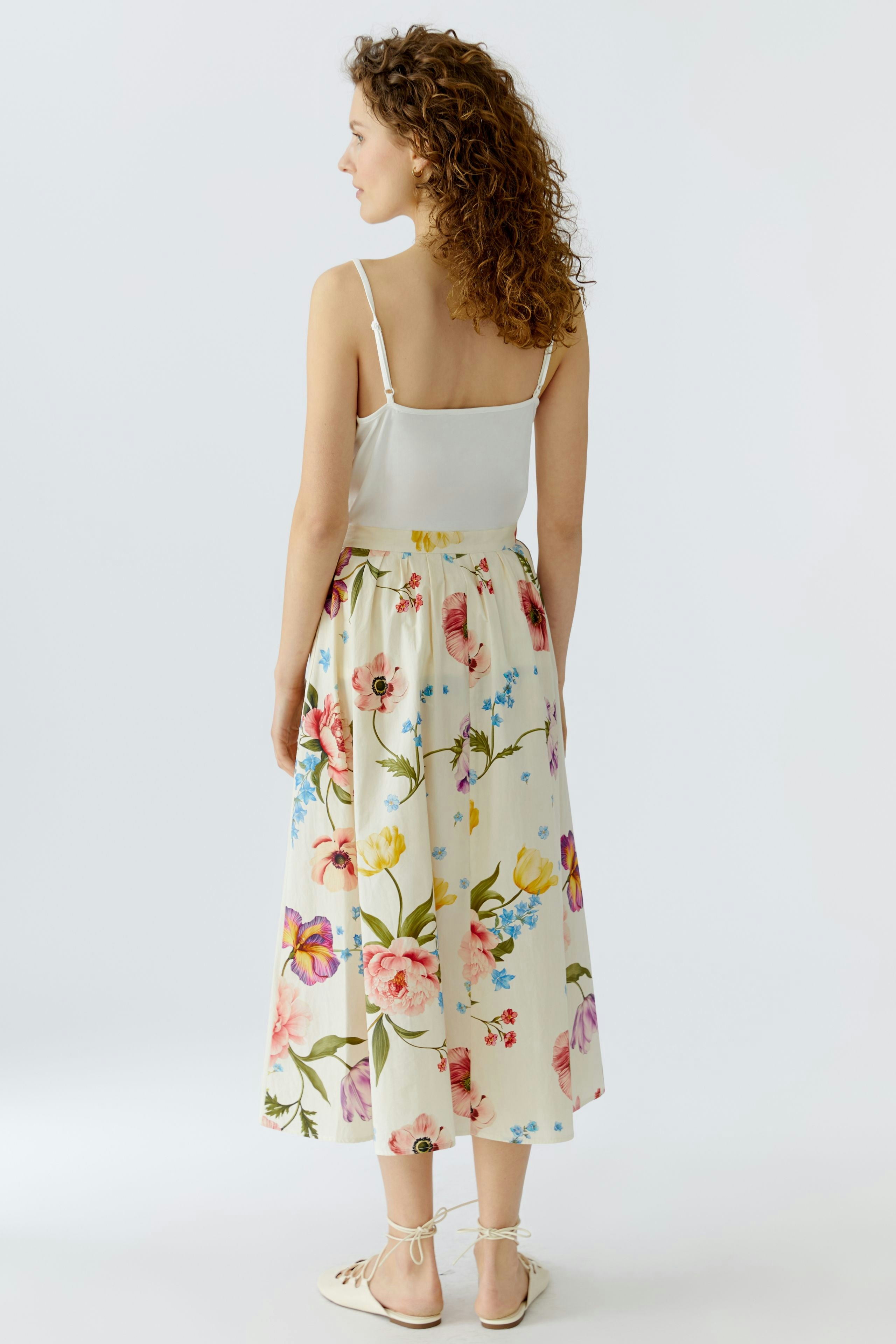 Floral midirock: Woman in a flowy skirt with colorful flowers, showcasing a relaxed summer style.