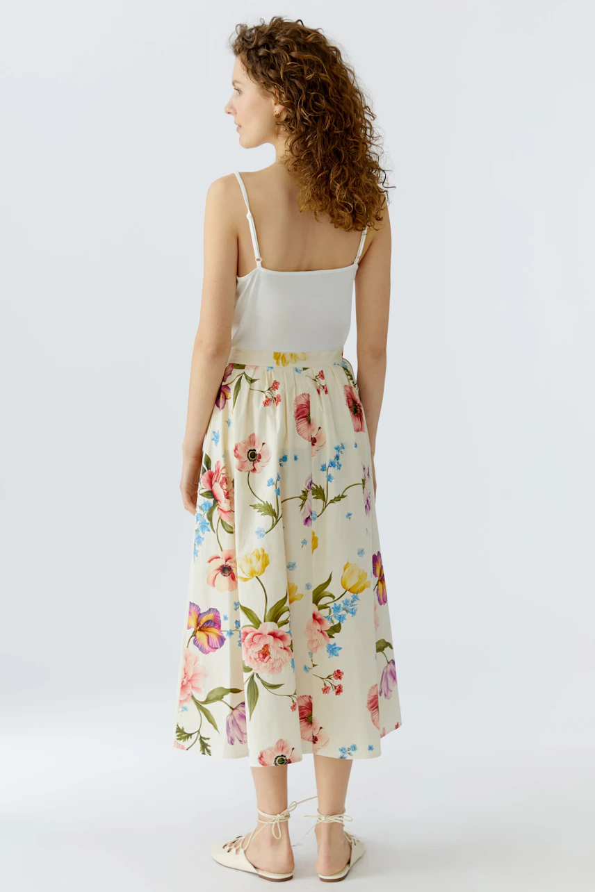 Floral midirock: Woman in a flowy skirt with colorful flowers, showcasing a relaxed summer style.