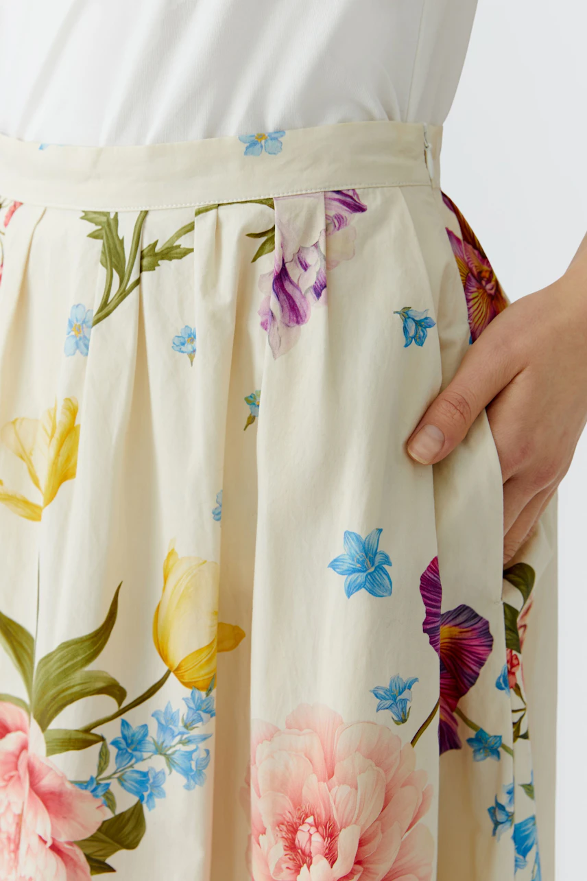 Floral midirock: Woman in a cream skirt with colorful flowers, showcasing a relaxed and vibrant style.