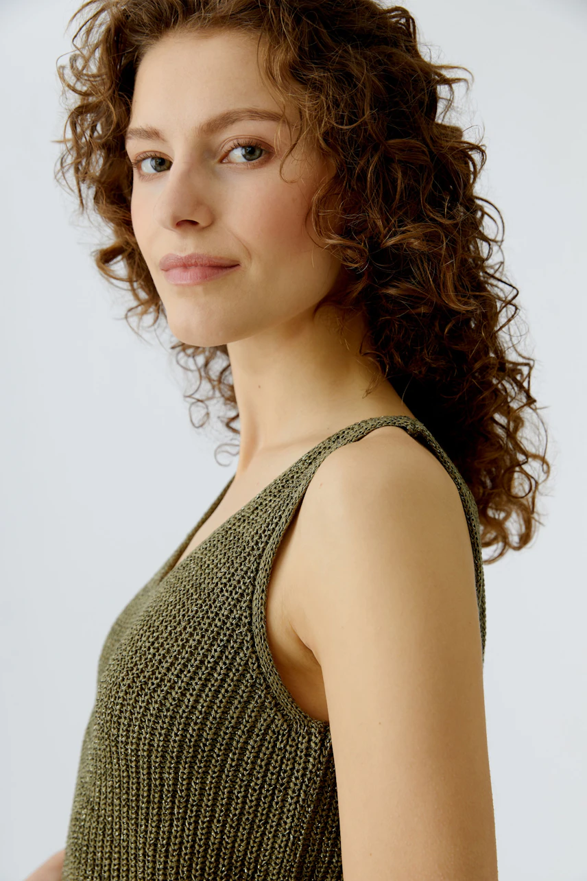 Casual women's top: Young woman in a green knitted top with a relaxed fit, showcasing a natural look.