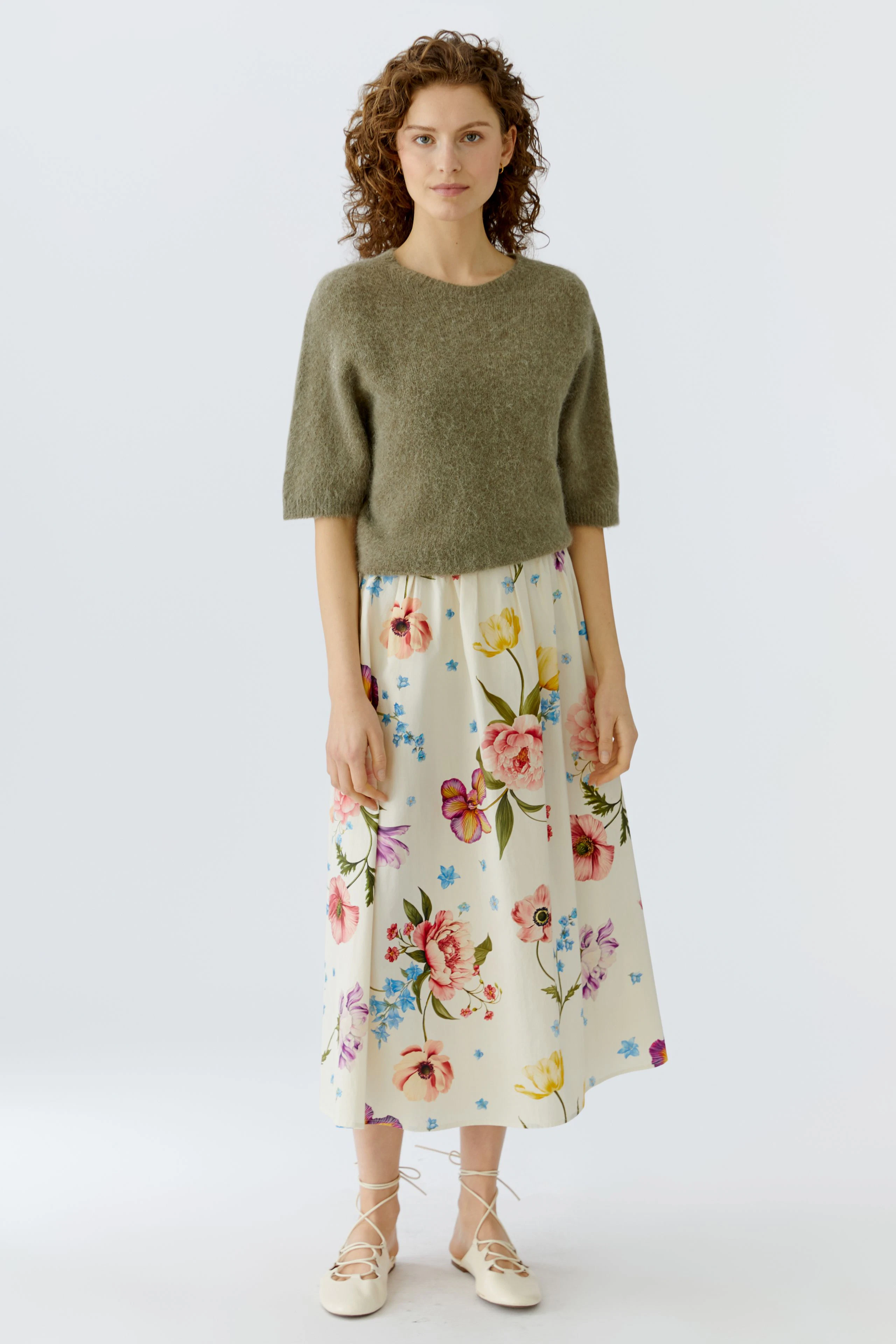 Damen-Pullover in Olivgrün: Frau trägt einen lässigen, kurzen Pullover zu einem floralen Rock.