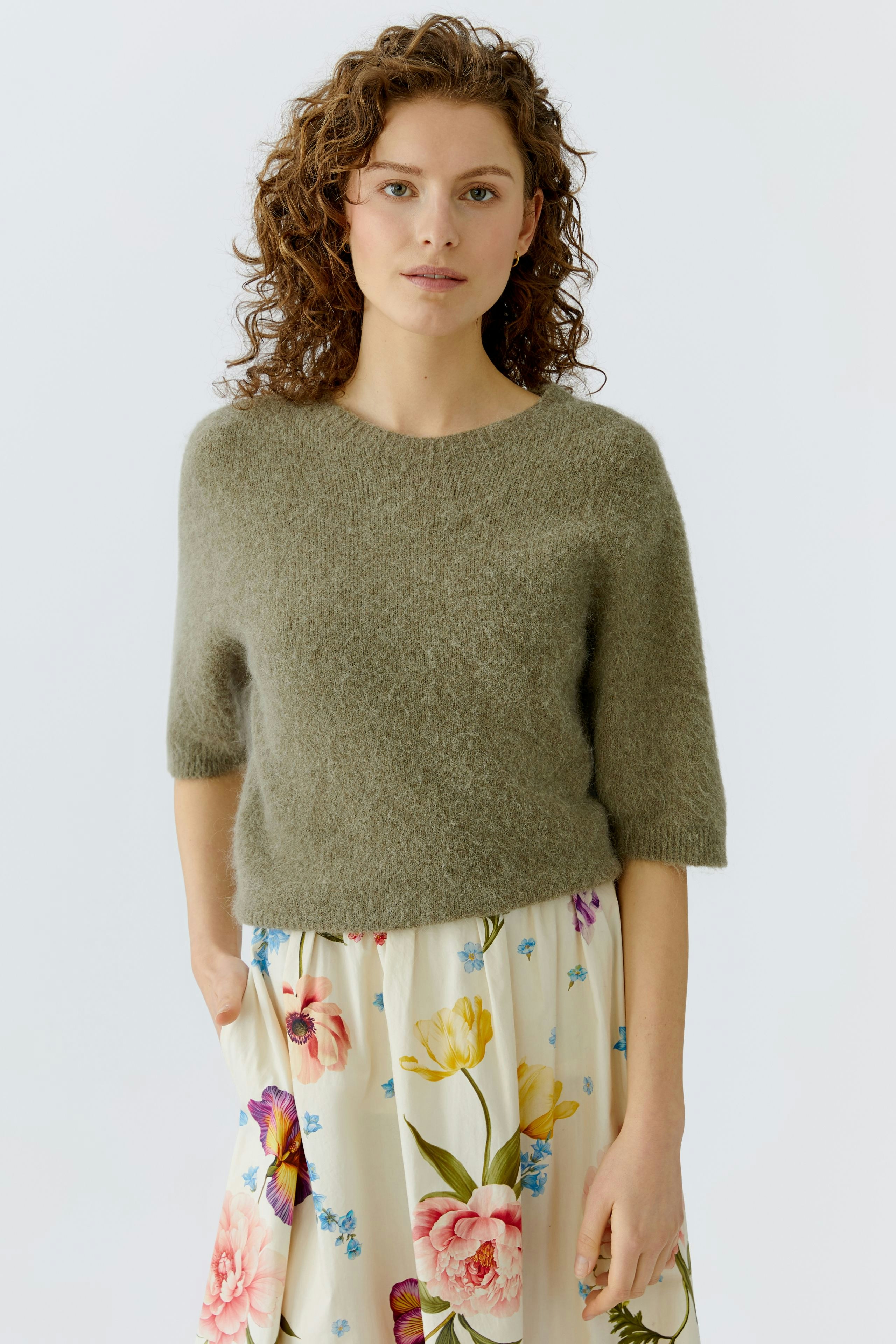 Casual women's pullover: A woman in a soft green pullover paired with a floral skirt.