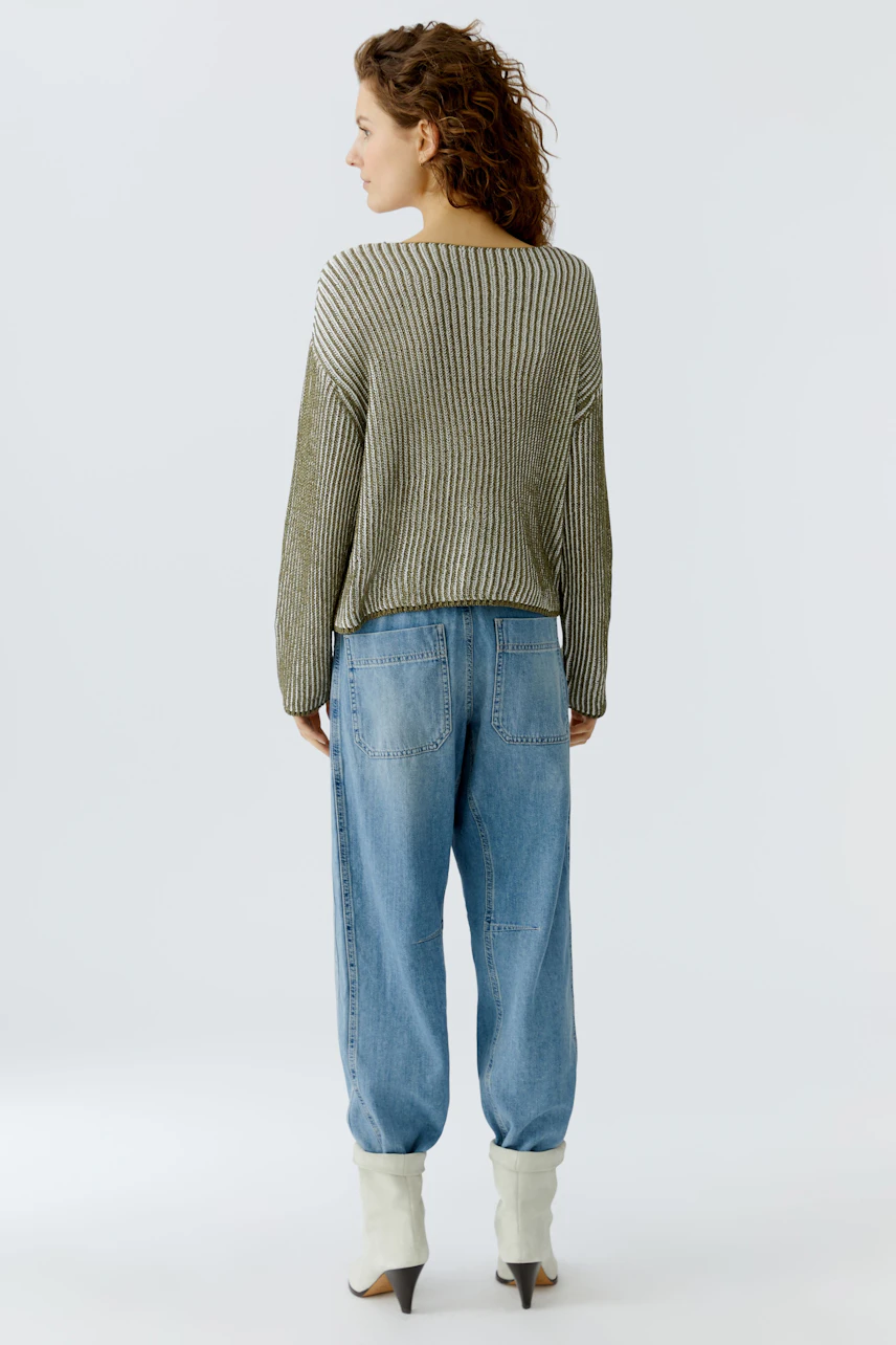 Damen-Pullover: Frau mit lockigem Haar trägt einen lässigen, gestreiften Pullover in Kombination mit Jeans.