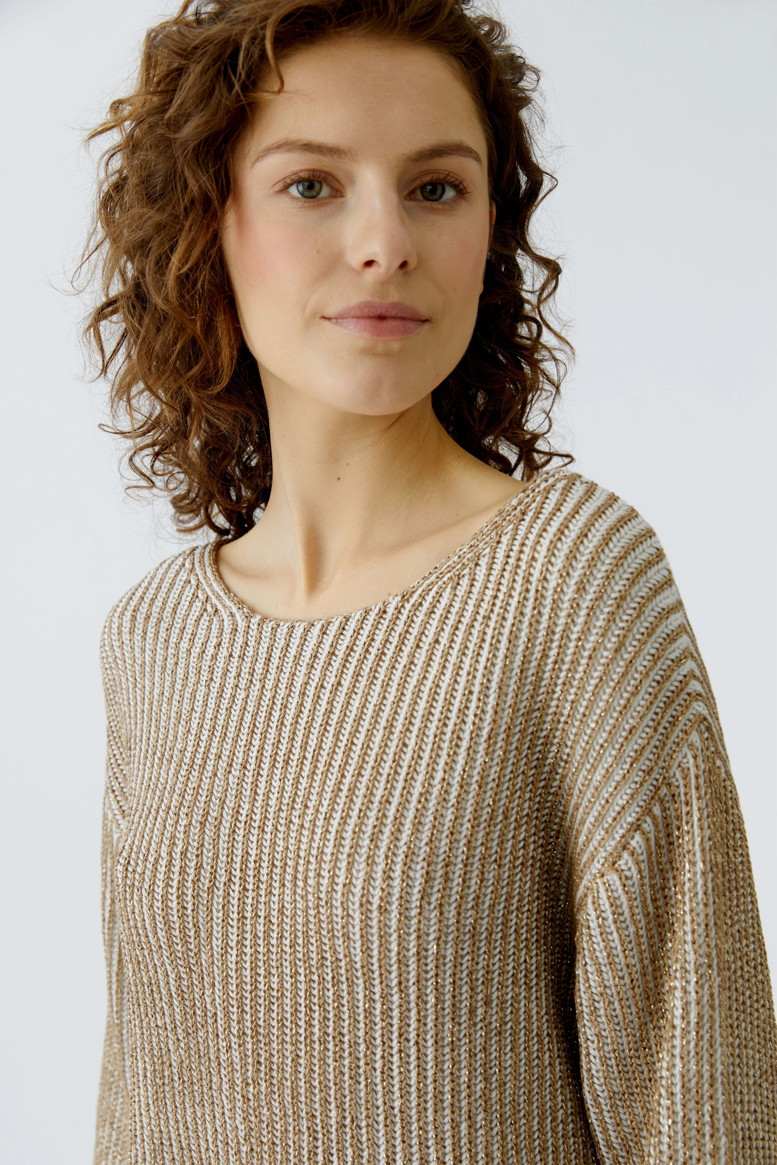 Damen-Pullover: Junge Frau mit lockigem Haar trägt einen goldfarbenen, gestreiften Pullover.