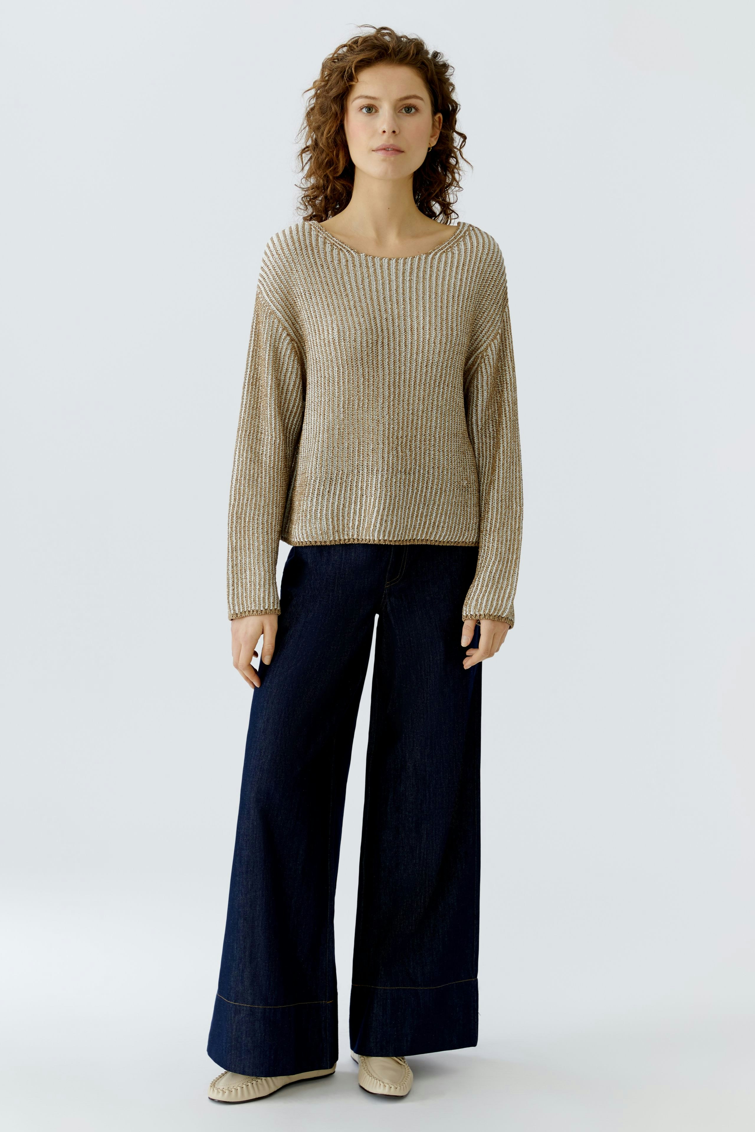 Casual women's pullover: A woman in a beige ribbed pullover paired with wide-leg jeans.