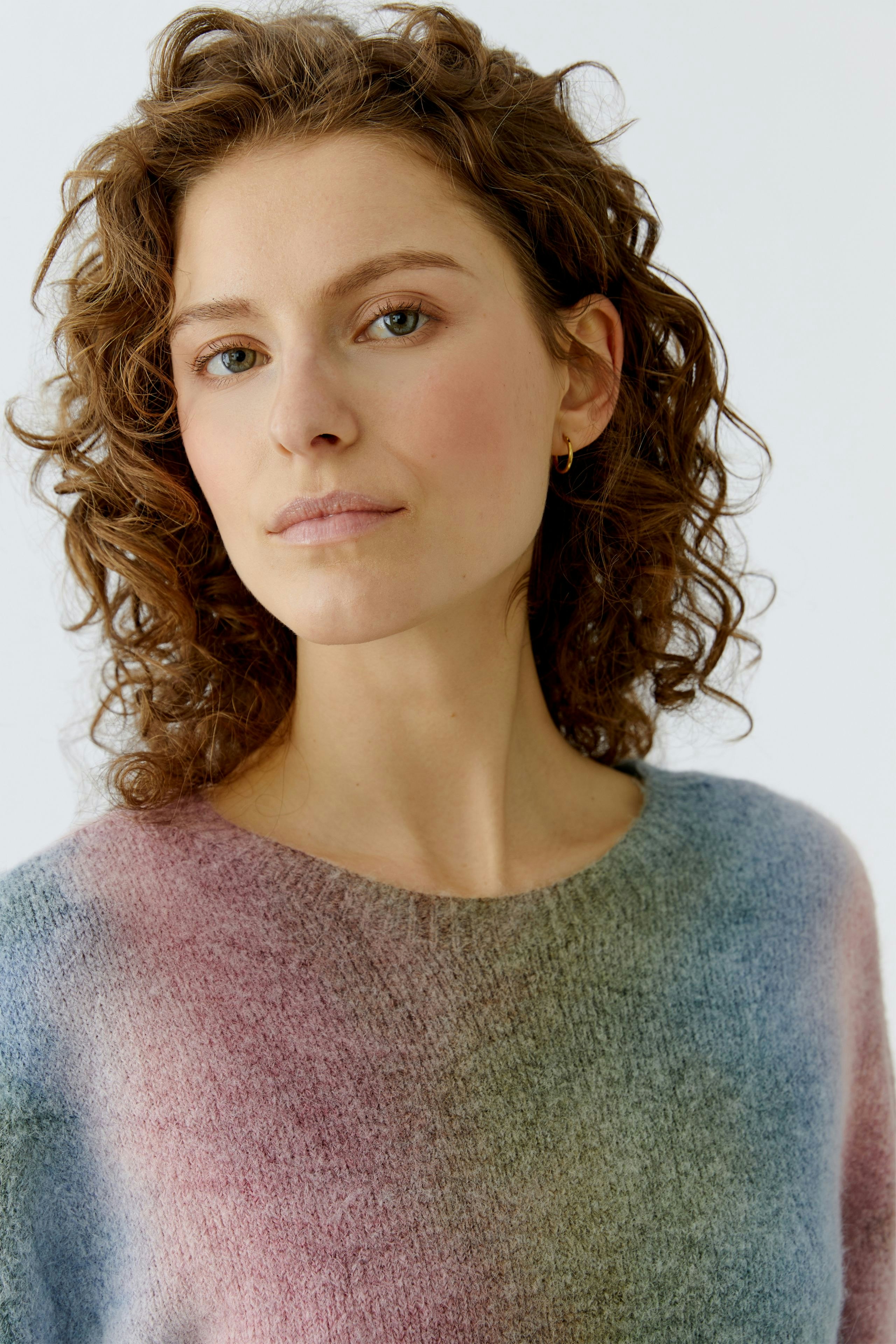 Casual women's pullover: Woman with curly hair in a soft, multicolored pullover, looking confidently at the camera.