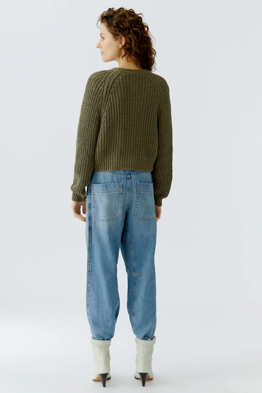 Casual women's cardigan: A woman in a green knitted cardigan paired with relaxed-fit jeans.