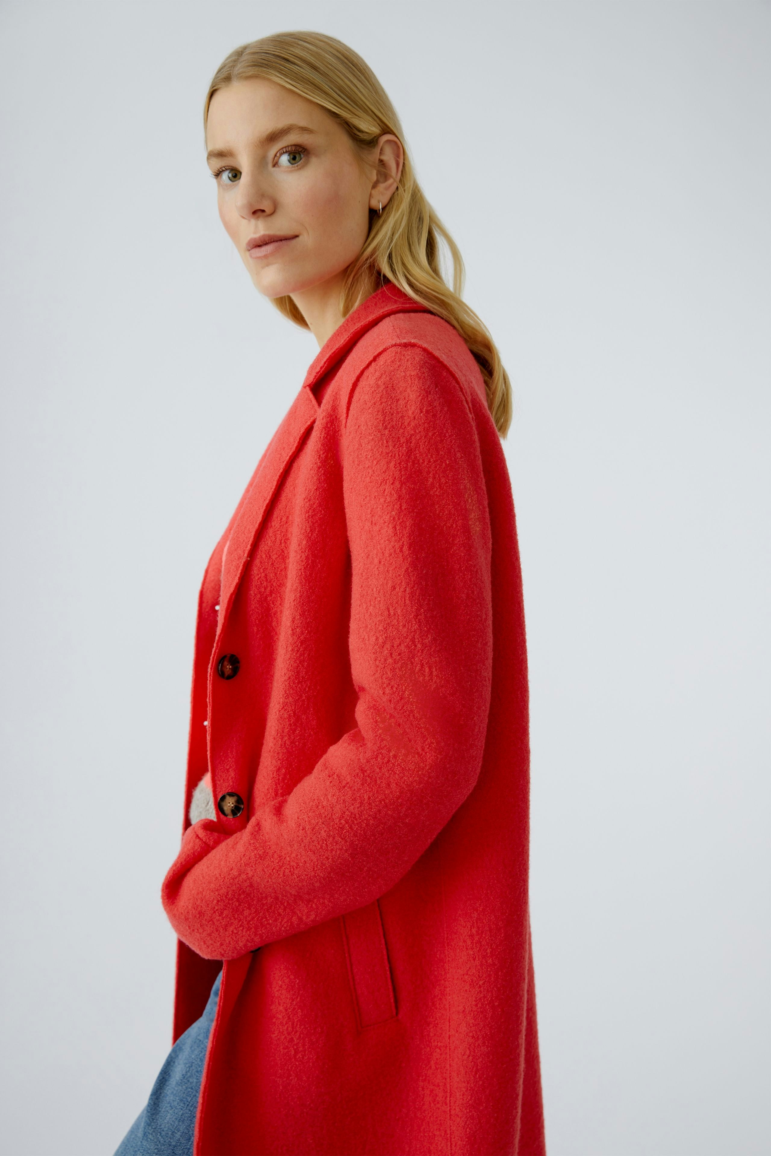 Modern women's wool coat: A woman in a vibrant red coat with buttons, styled casually.
