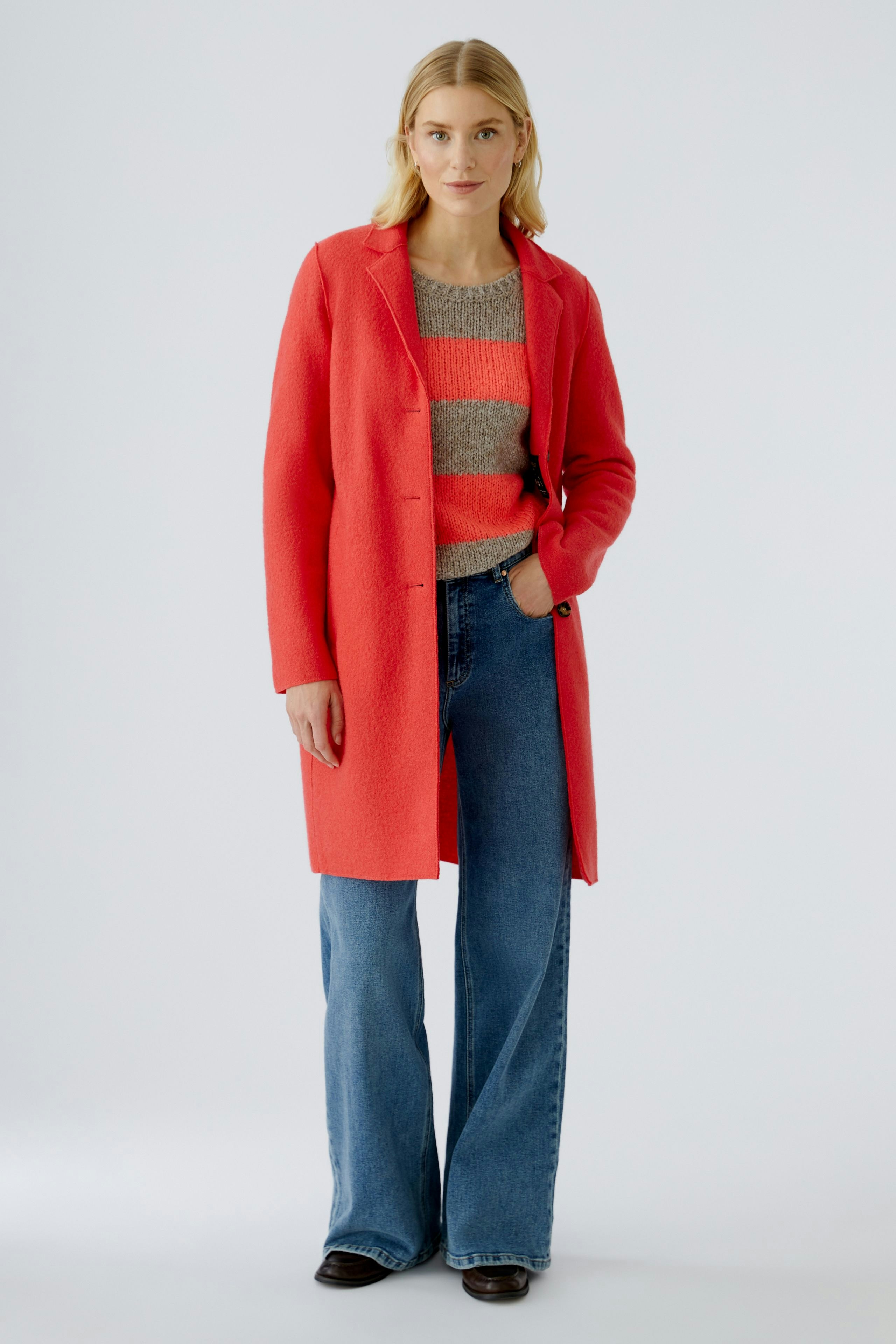 Modern women's wool coat: Woman in a bright red coat over a striped pullover and wide jeans.