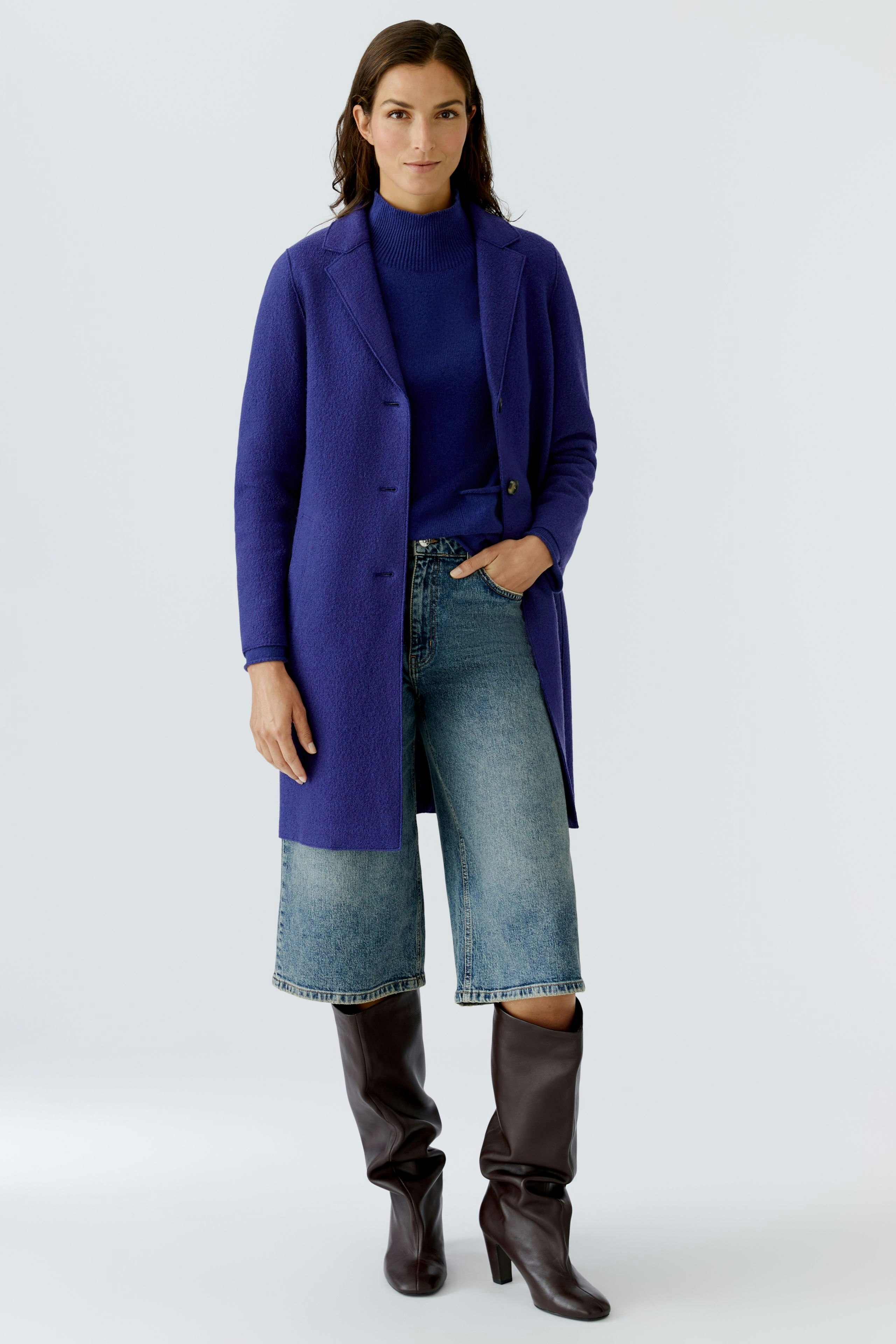 Wool coat: Woman in a vibrant purple wool coat over a striped pullover and brown pants.