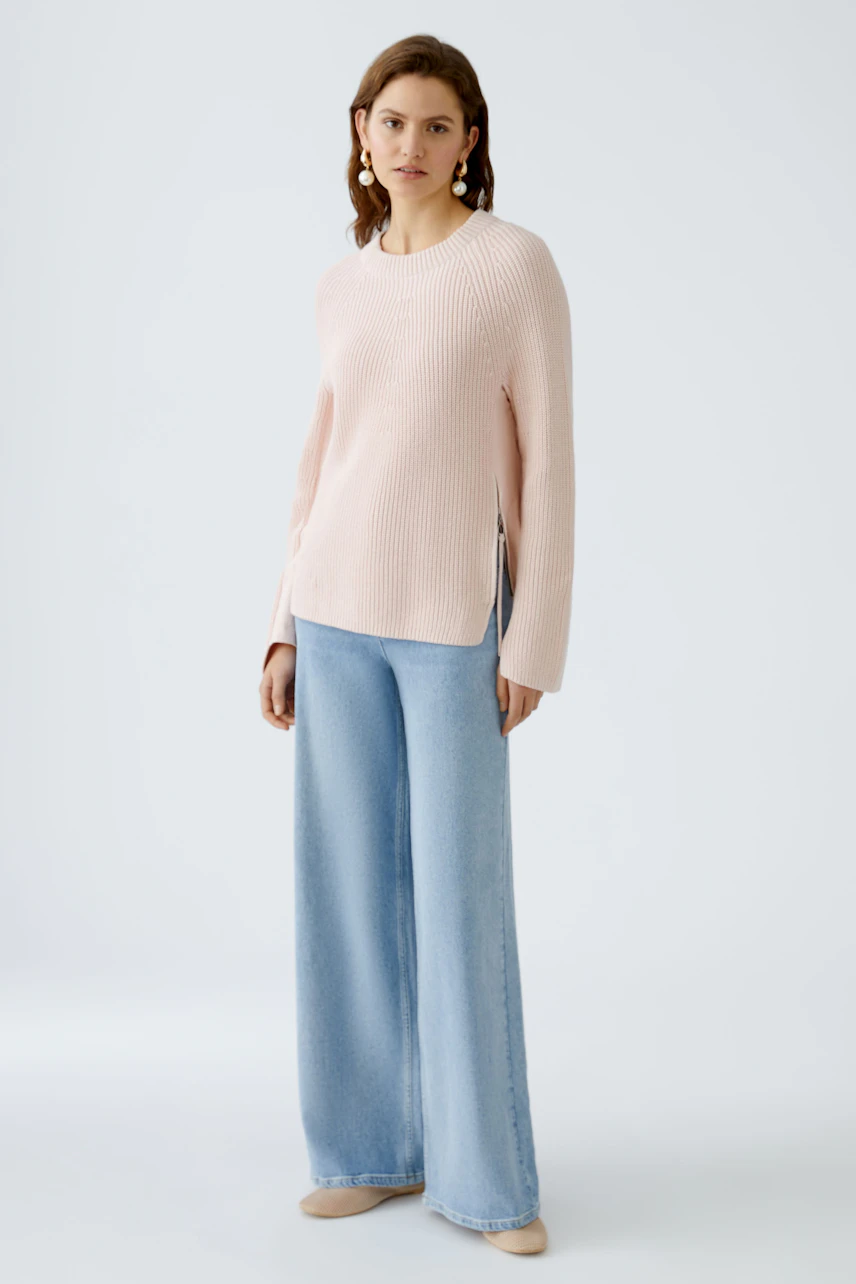 Damen-Pullover: Frau in zartem rosa Strickpullover mit lässigem Schnitt und seitlichen Schlitzen.