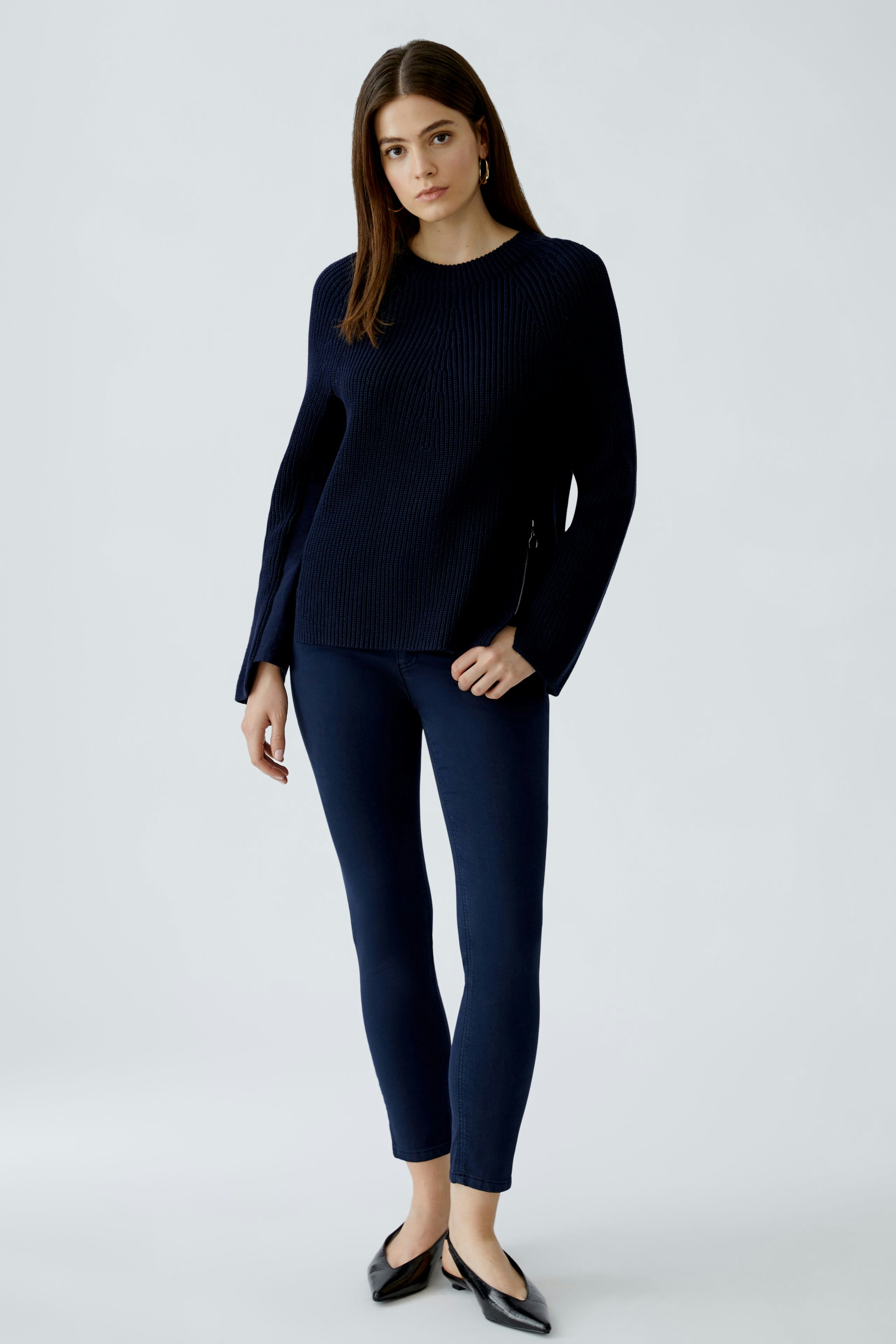 Modern women's pullover: A woman in a navy ribbed pullover paired with light jeans.