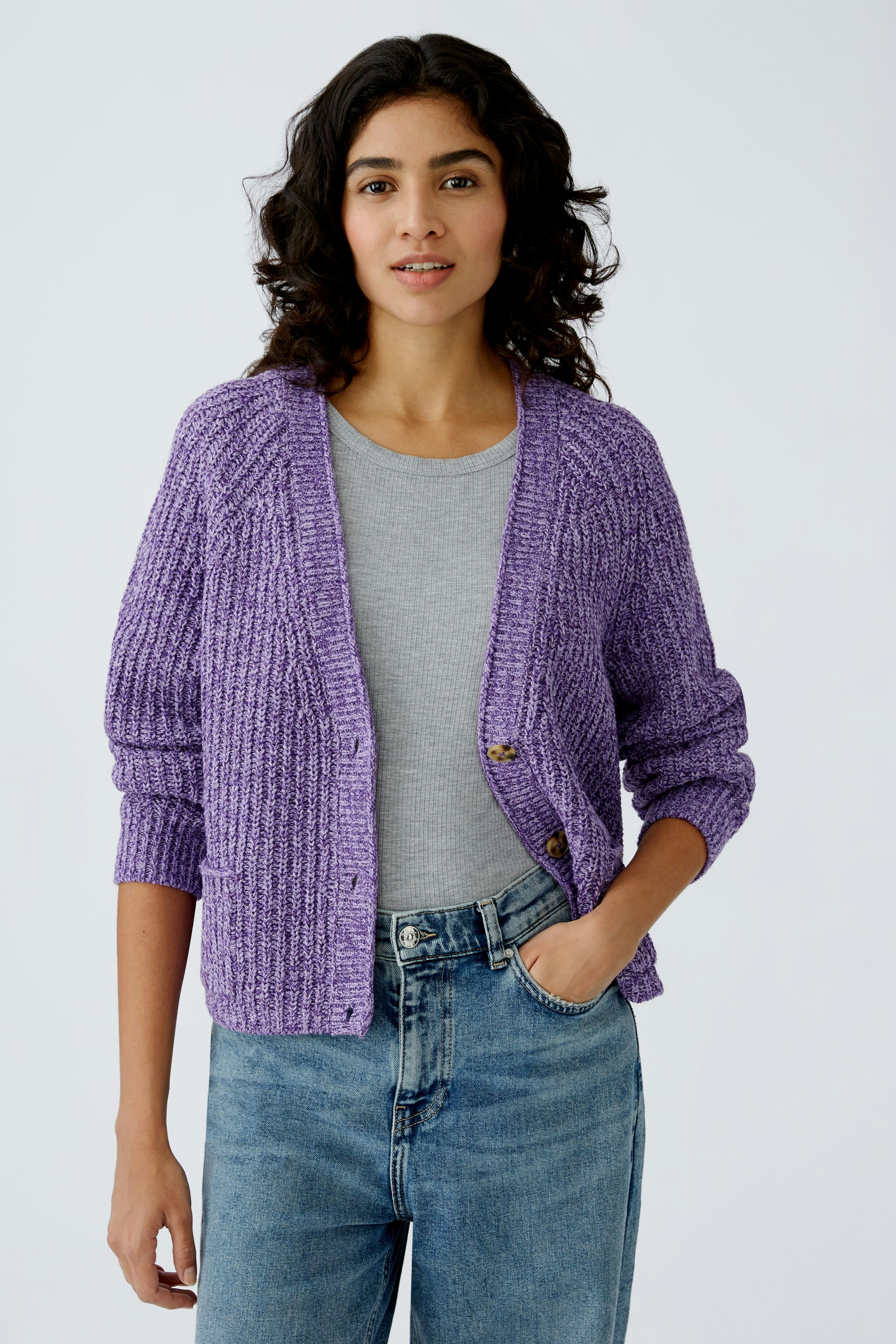 Stylish women's cardigan: A woman in a purple knitted cardigan over a gray top and jeans.