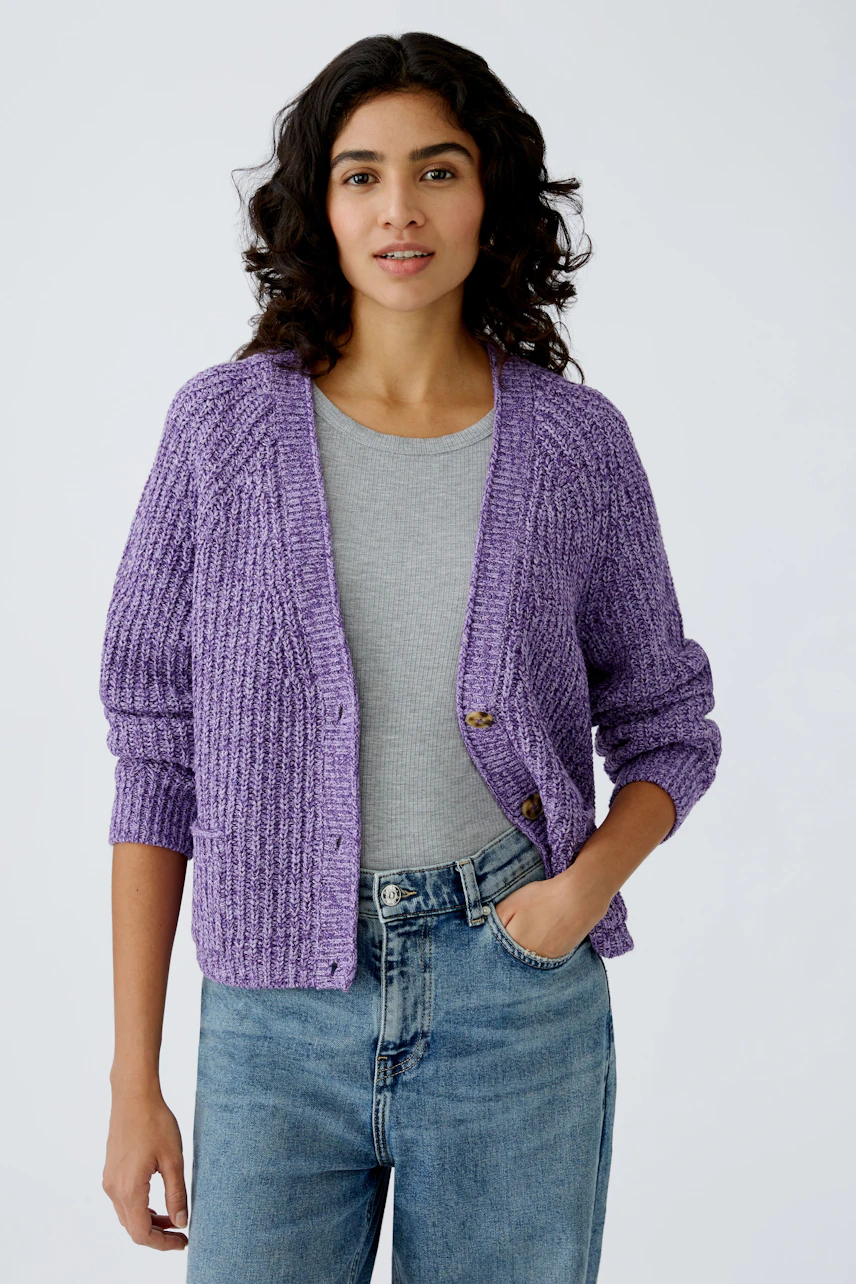 Stylish women's cardigan: A woman in a purple knitted cardigan over a gray top and jeans.