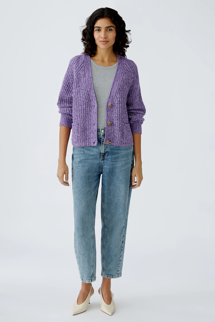 Stylish women's cardigan: A woman in a purple knitted cardigan over a gray top and jeans.