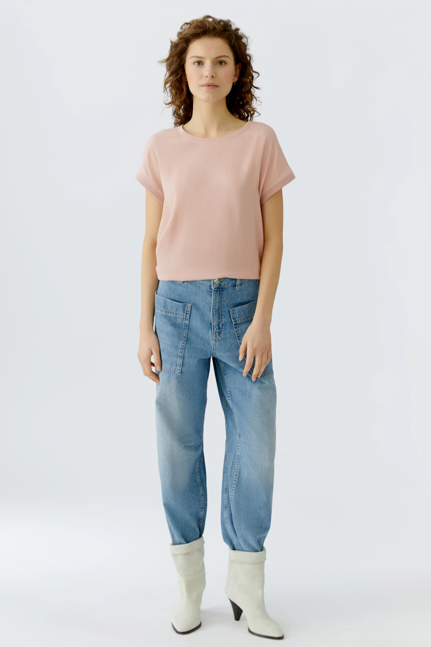 Casual women's blouse shirt: A woman in a light pink blouse paired with relaxed-fit jeans.