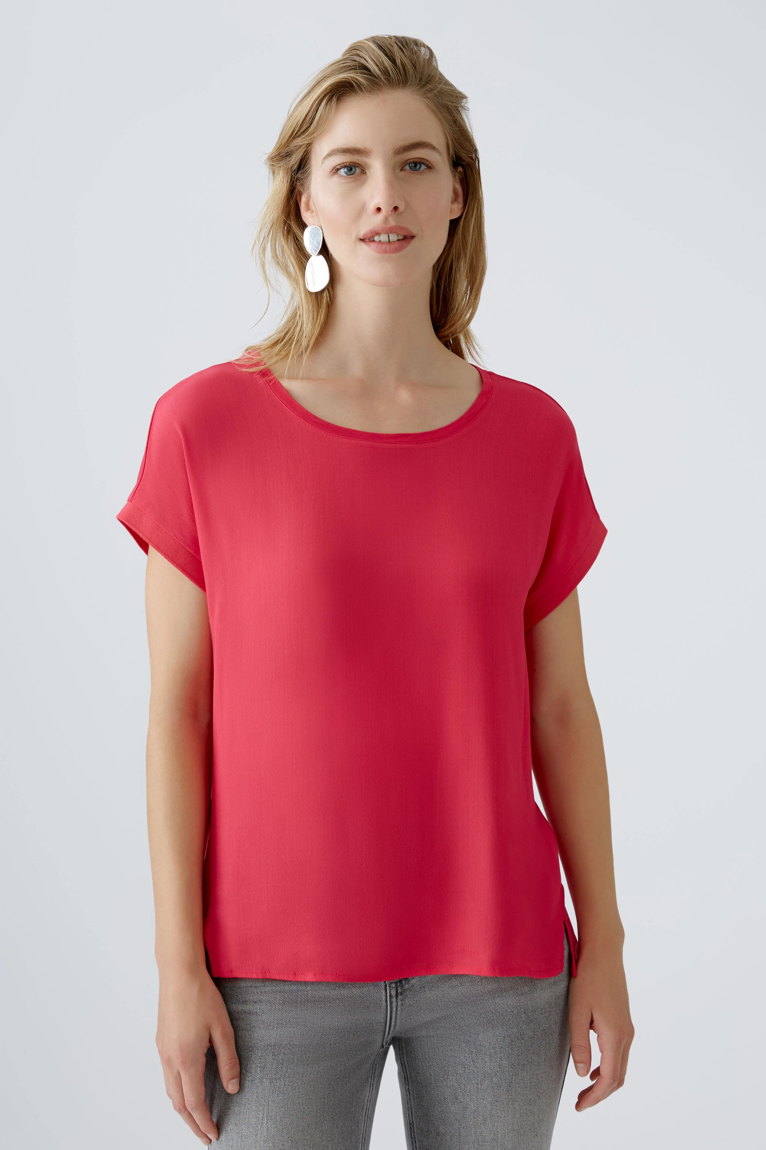 Luftiges Blusenshirt: Frau trägt ein rotes, lässiges Shirt mit kurzen Ärmeln und lässigem Schnitt.