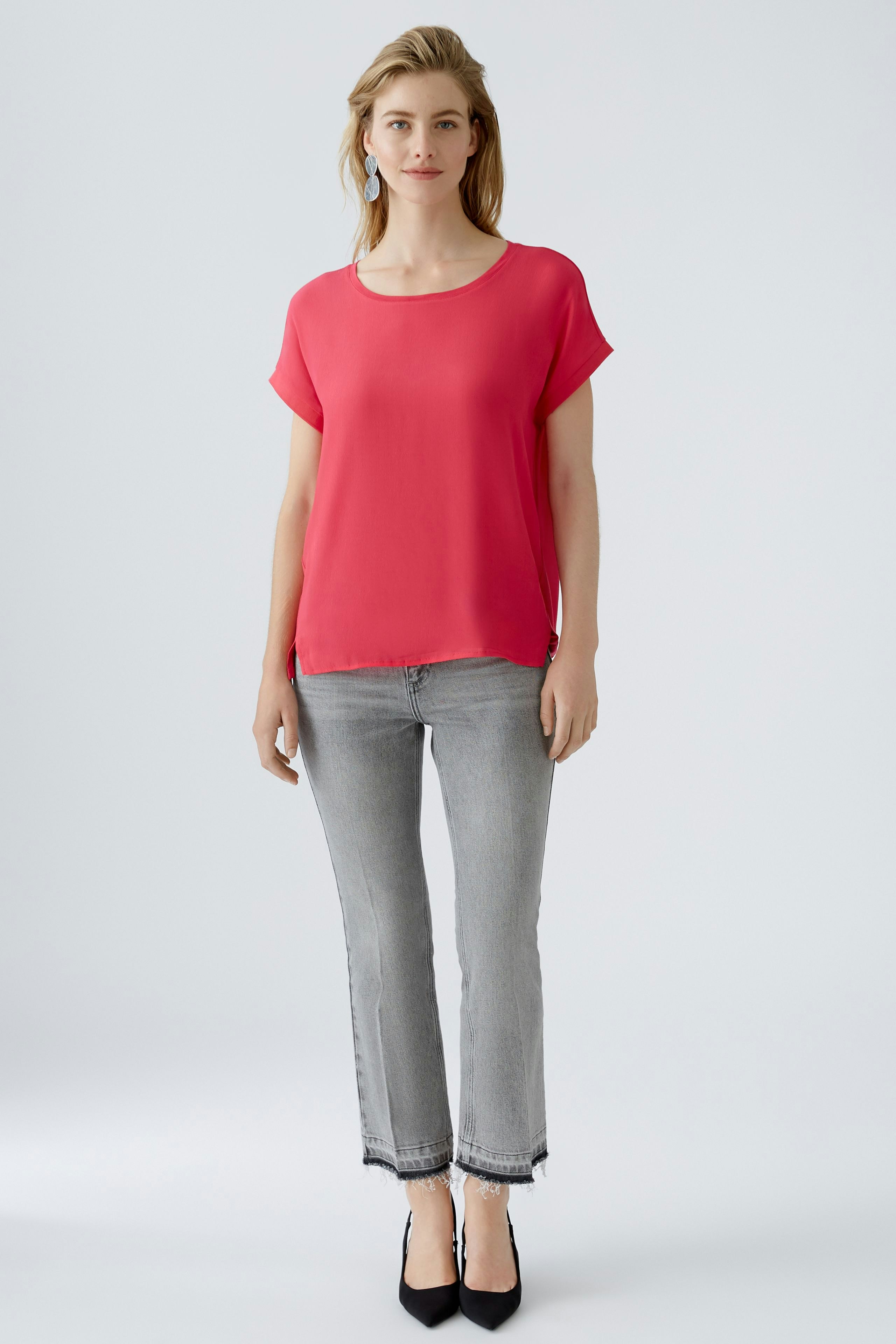 Stylish blouse shirt: A woman in a vibrant pink blouse shirt paired with gray jeans and heels.