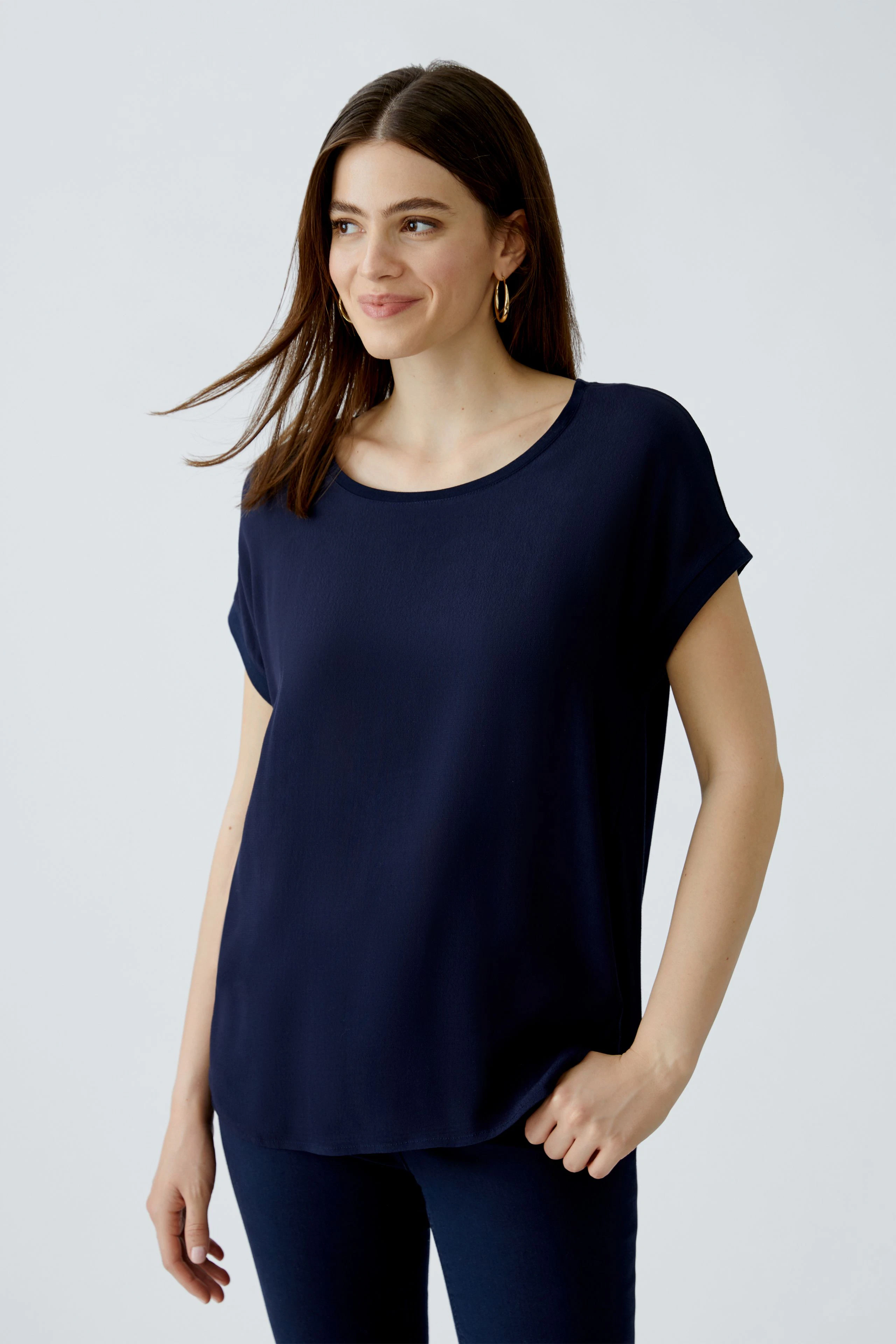 Casual women's blouse shirt: Woman in a navy blue top with rolled sleeves, smiling confidently.