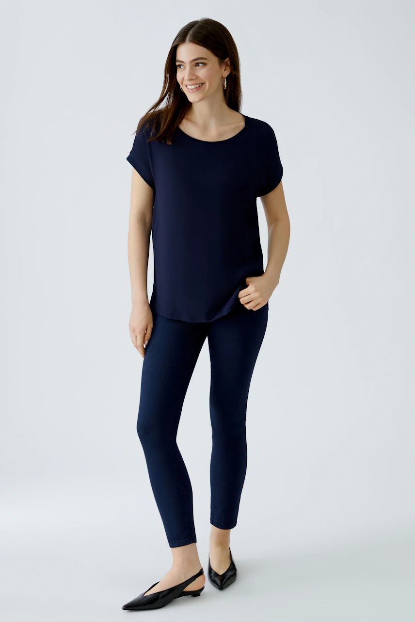 Bequeme Blusenshirt für Damen: Frau in navyfarbener Bluse und schmalen Hosen, lächelt entspannt.