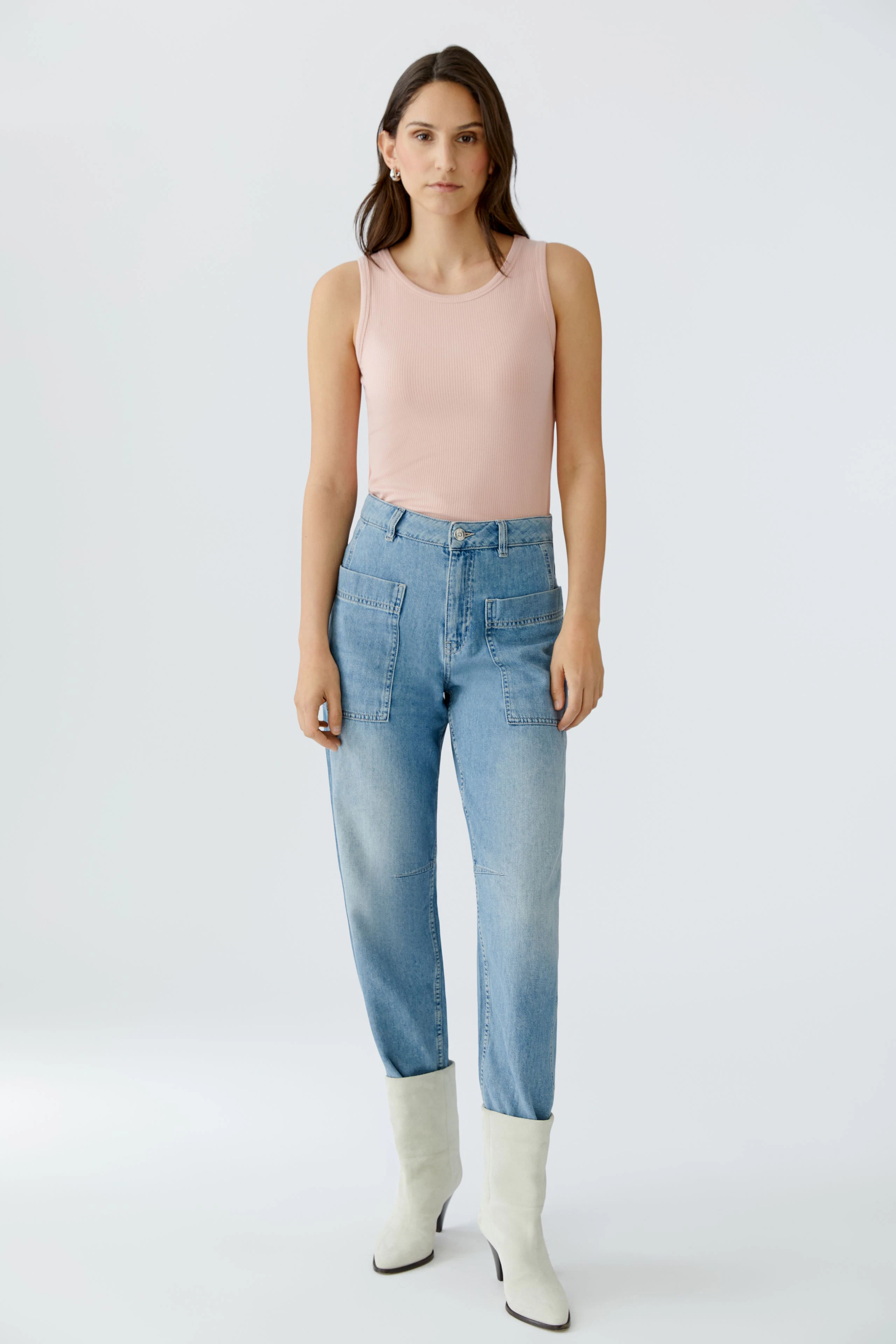 Casual women's top: A woman in a light pink sleeveless top paired with high-waisted jeans.