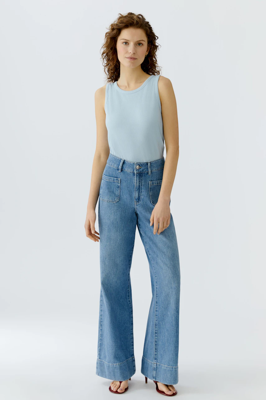 Casual women's top: A woman in a light blue sleeveless top paired with wide-leg jeans.