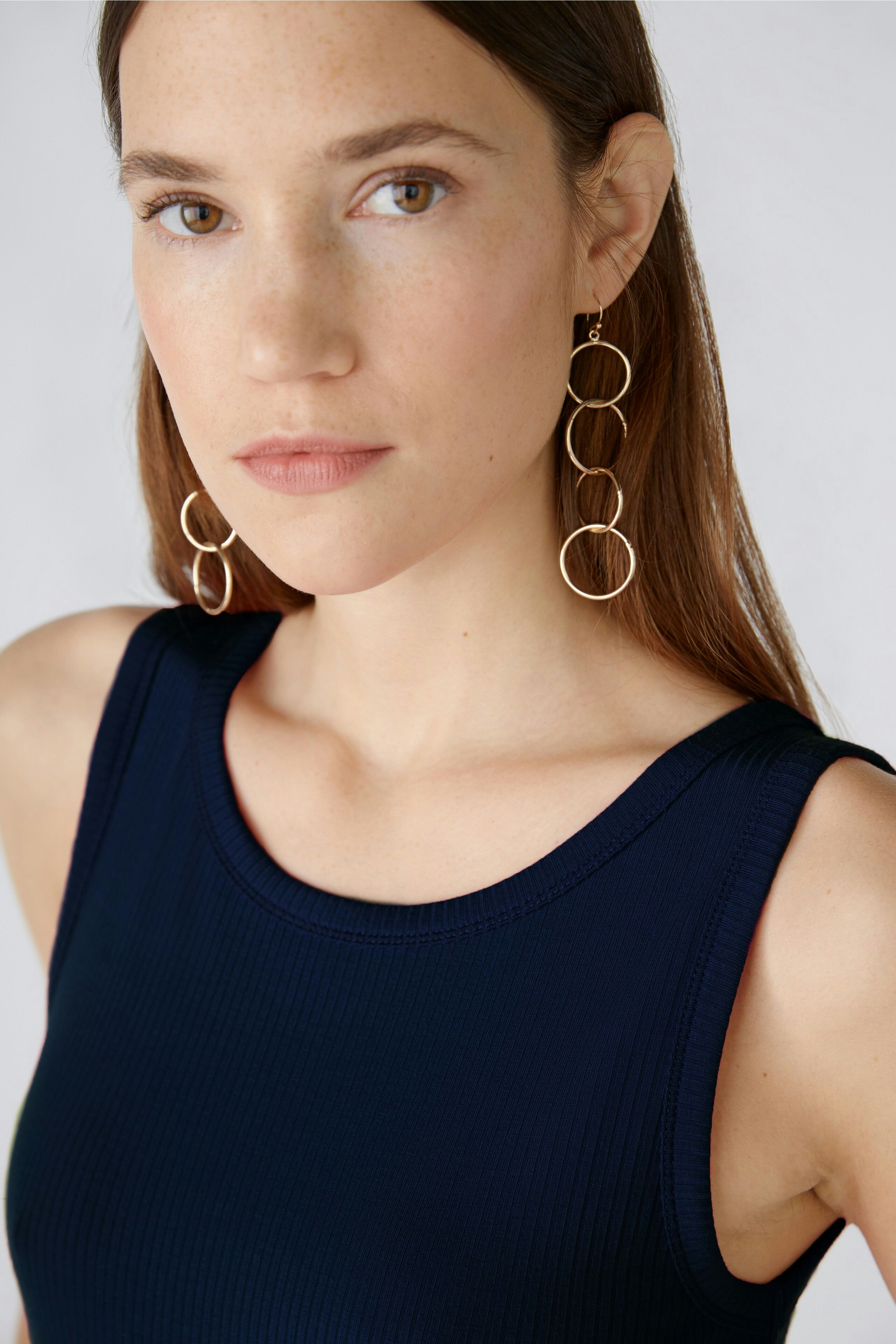 Elegantes Damen-Top: Frau mit schmalem, navyfarbenem Top und modischen Ohrringen blickt direkt in die Kamera.
