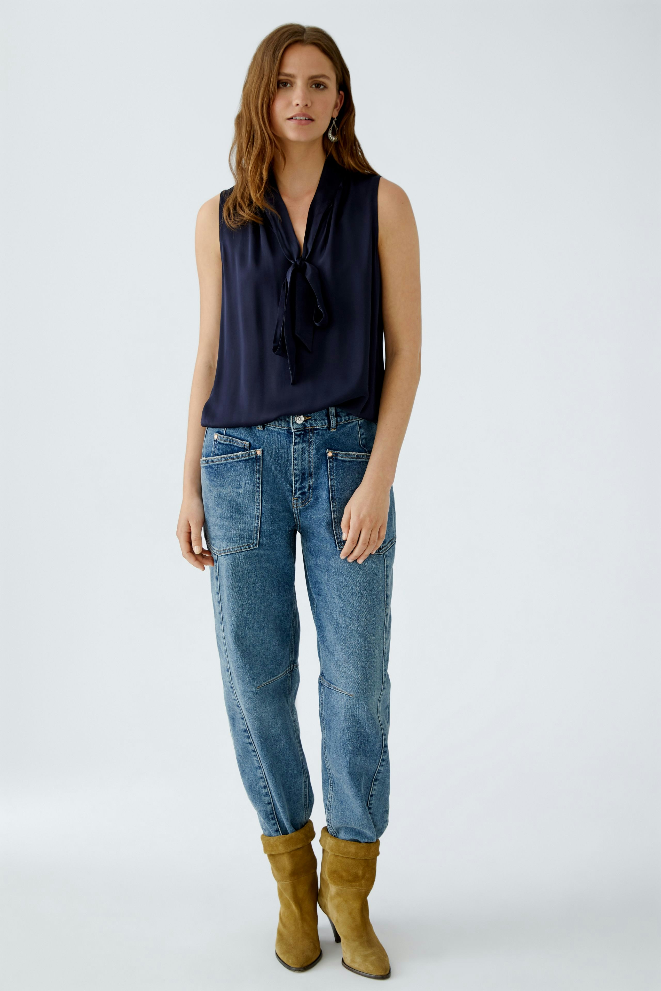 Casual women's blouse: A woman in a navy tie-neck blouse paired with relaxed-fit jeans.