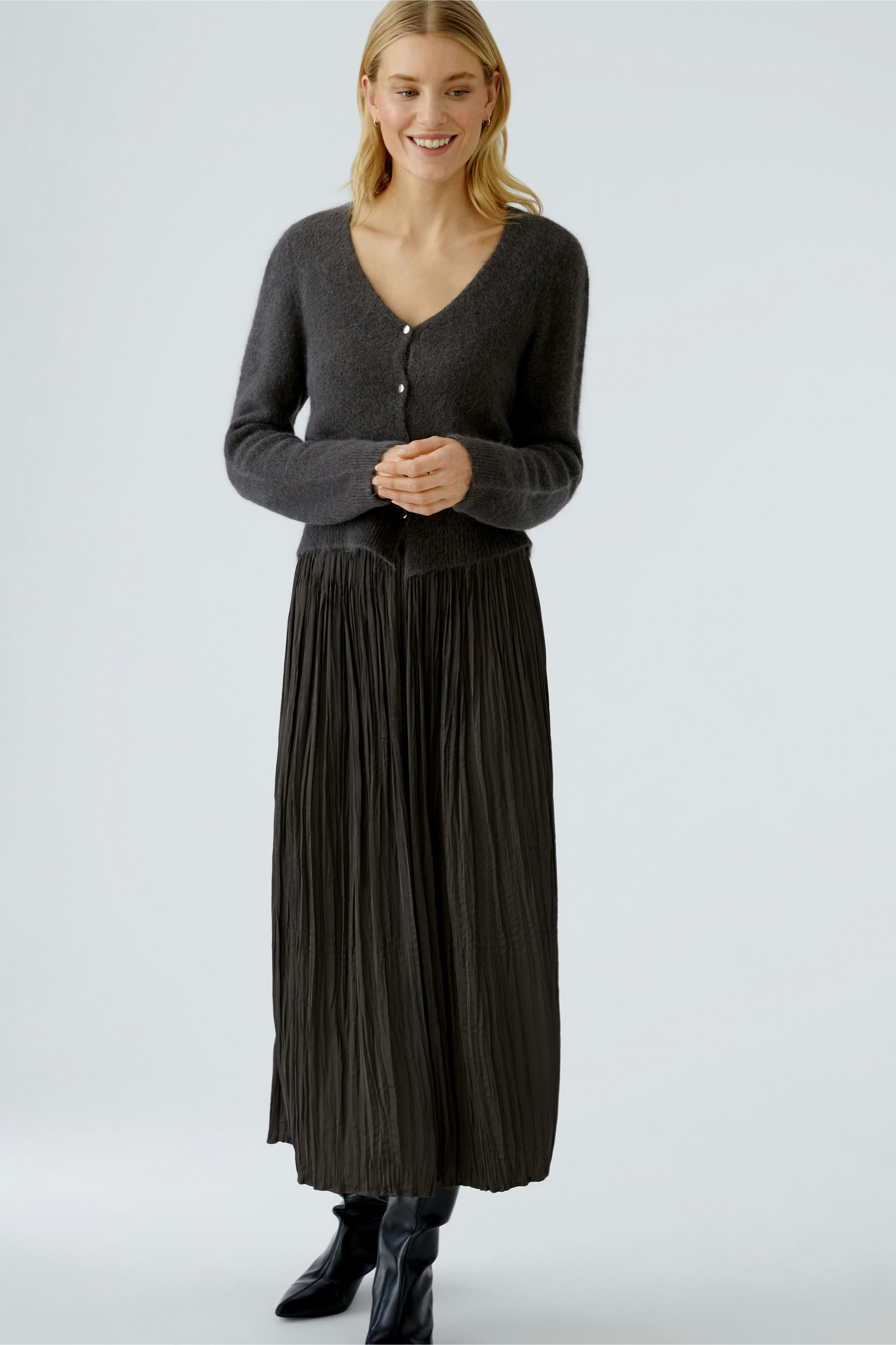 Casual maxi skirt: Woman in a pleated black maxi skirt paired with a cozy cardigan.