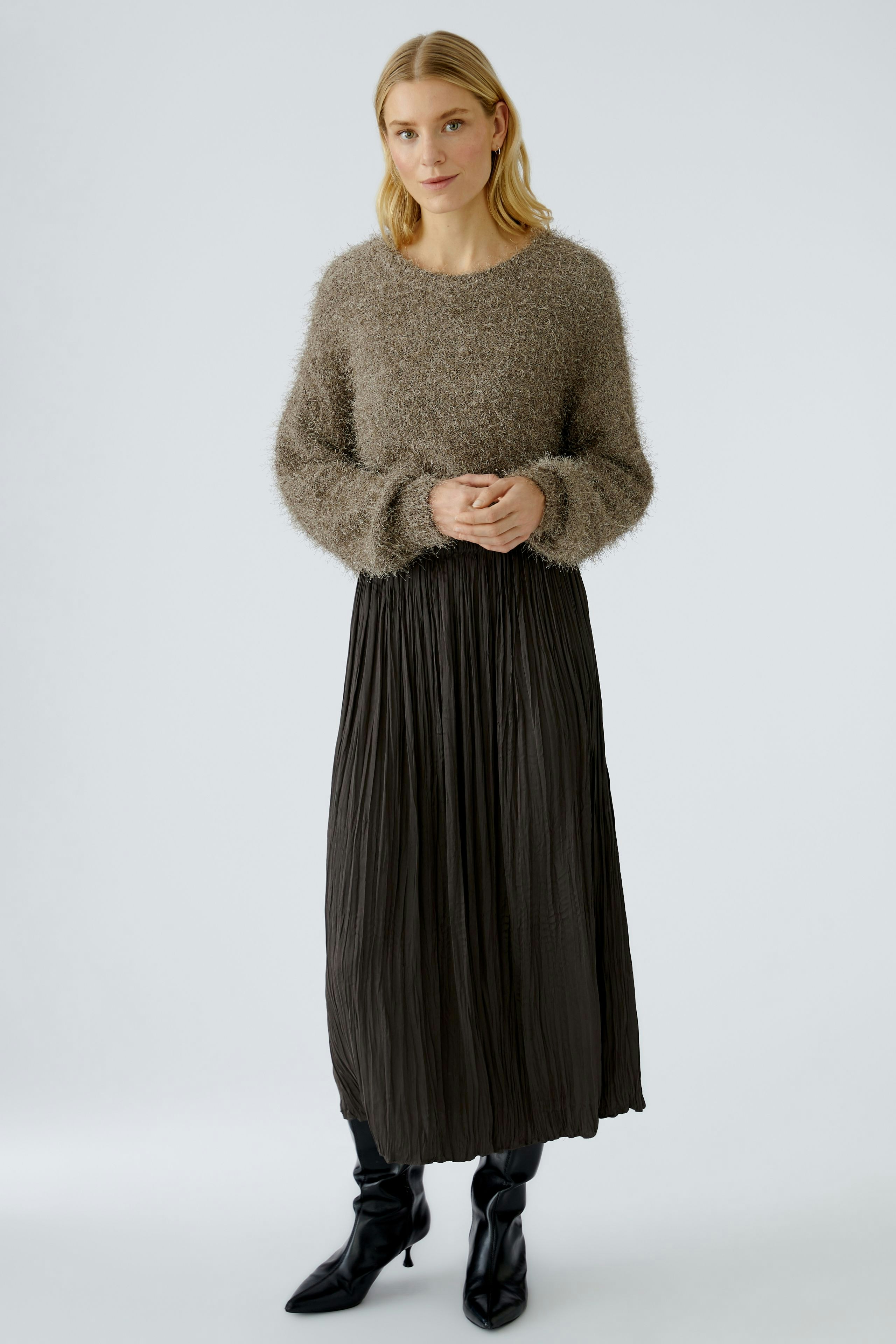 Casual maxi skirt: Woman in a soft, pleated black maxi skirt paired with a cozy, fluffy pullover.