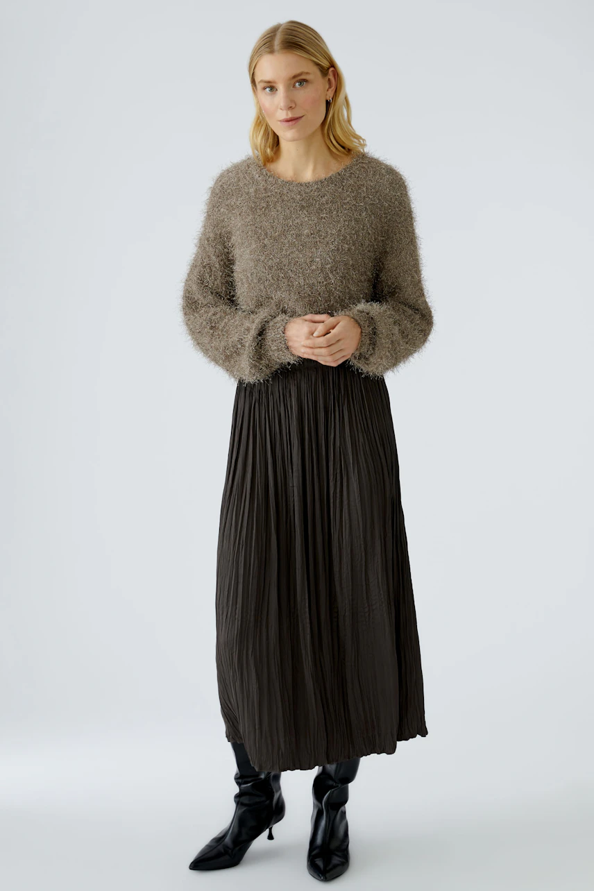Casual maxi skirt: Woman in a soft, pleated black maxi skirt paired with a cozy, fluffy pullover.