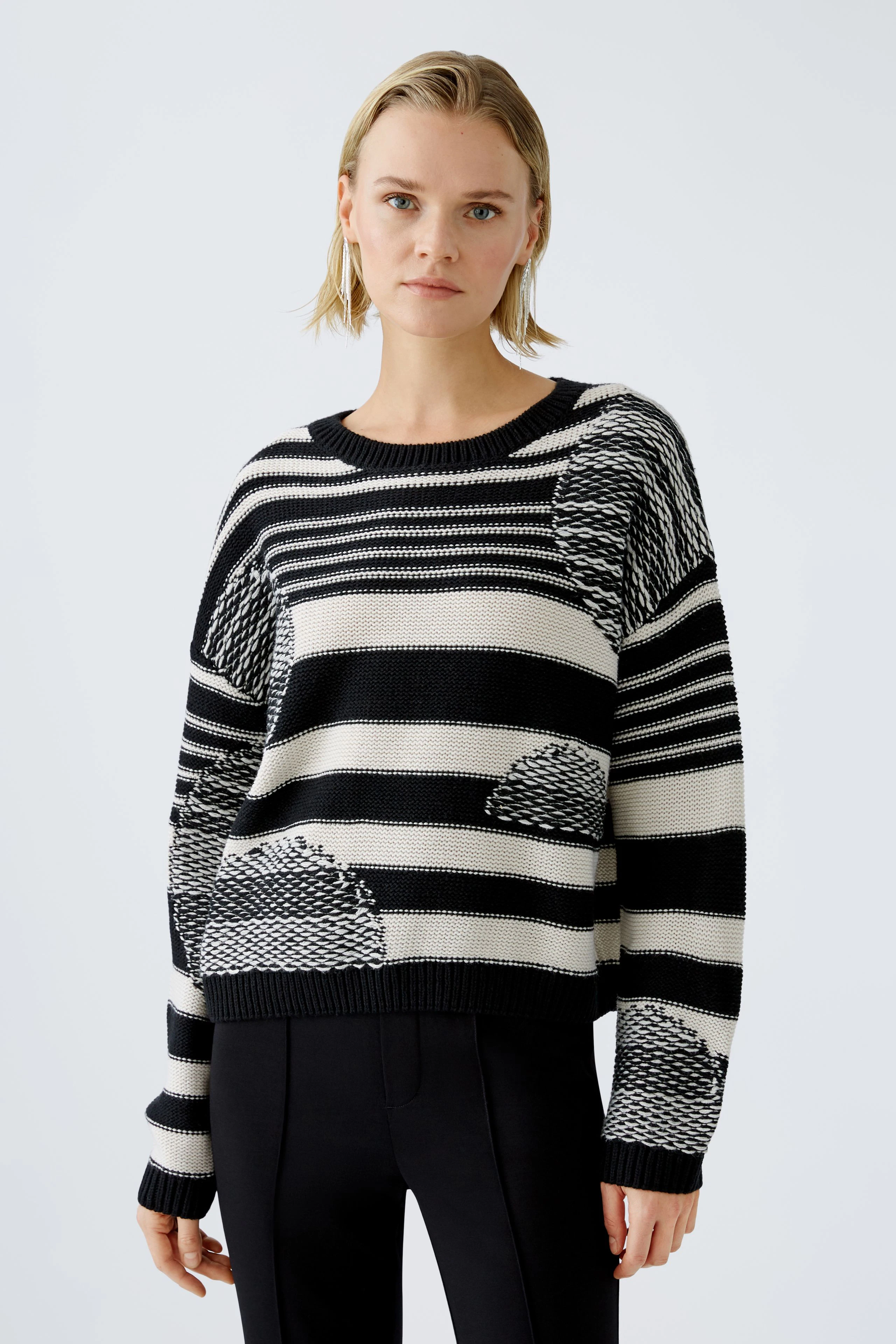 Modern pullover: Woman in a striped black and white pullover with unique patterns, exuding style.
