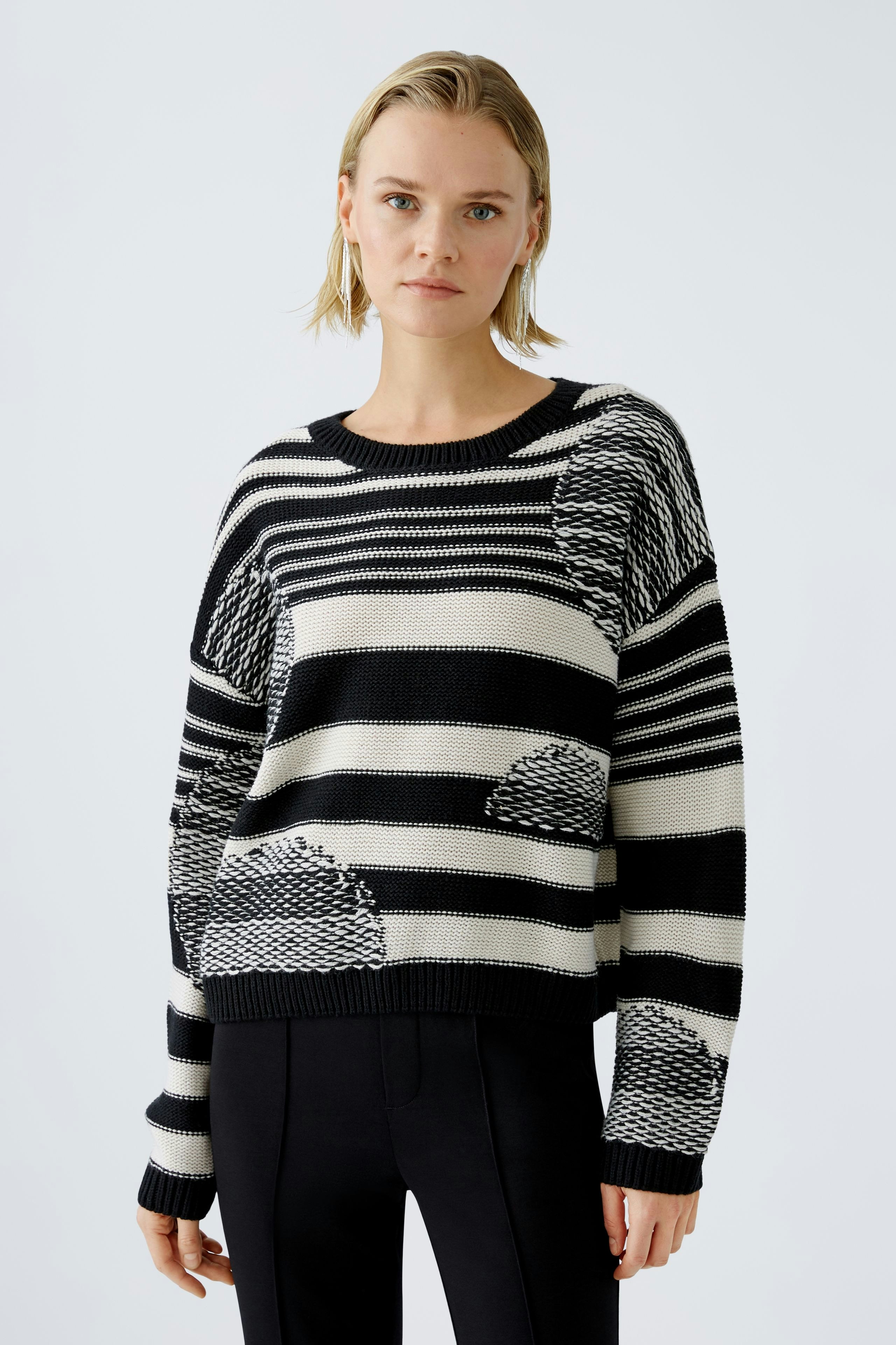Modern pullover: Woman in a striped black and white pullover with unique patterns, exuding style.