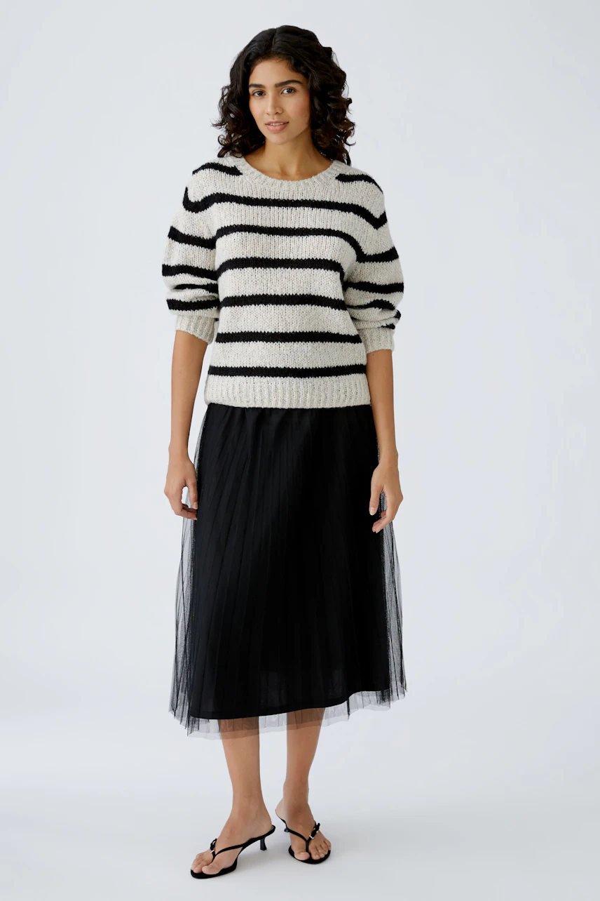 Damen-Pullover: Frau in gestreiftem, lässigem Strickpullover mit schwarzem Rock und Sandalen.