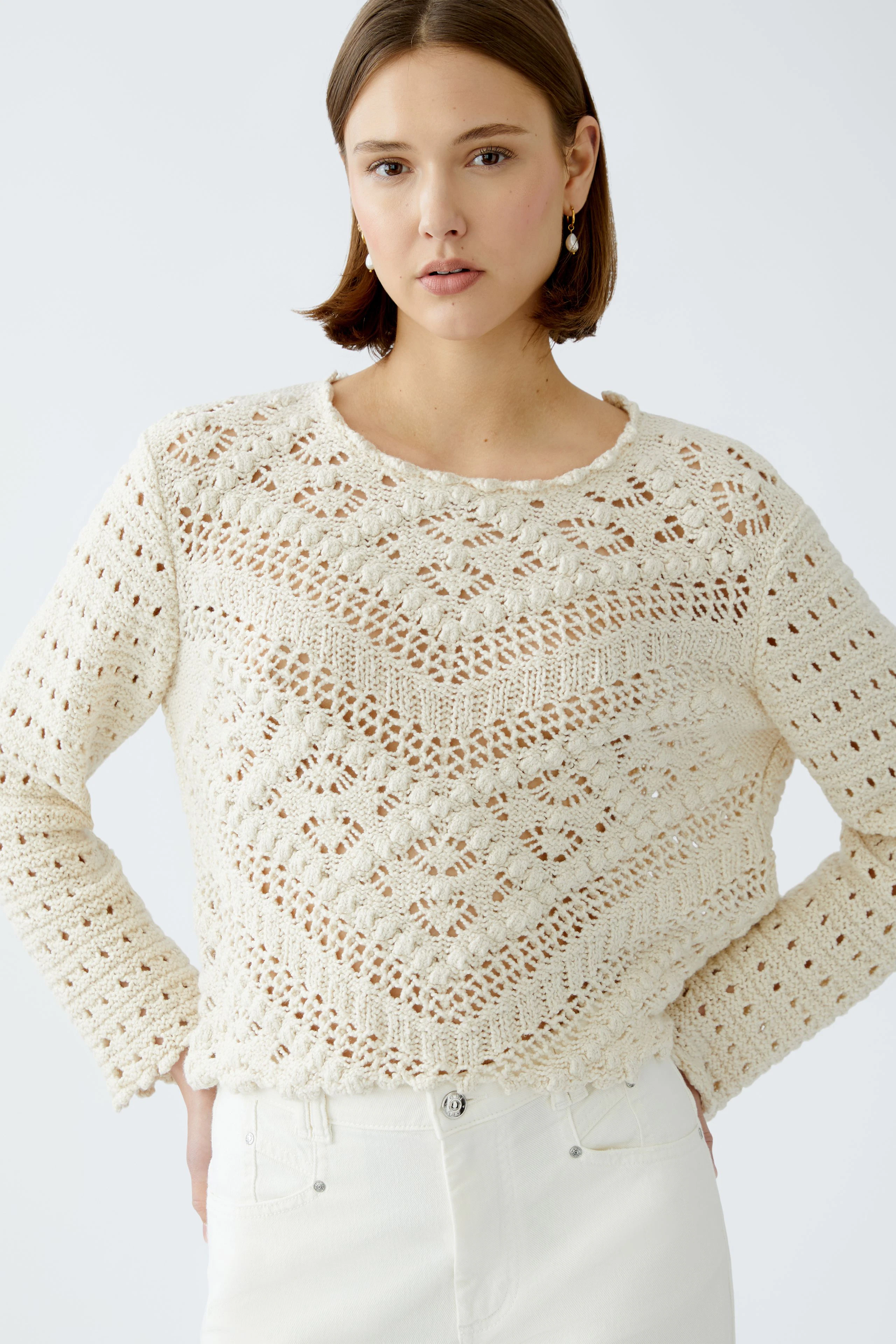 Stylish women's pullover: A woman in a cream knitted pullover with intricate patterns.