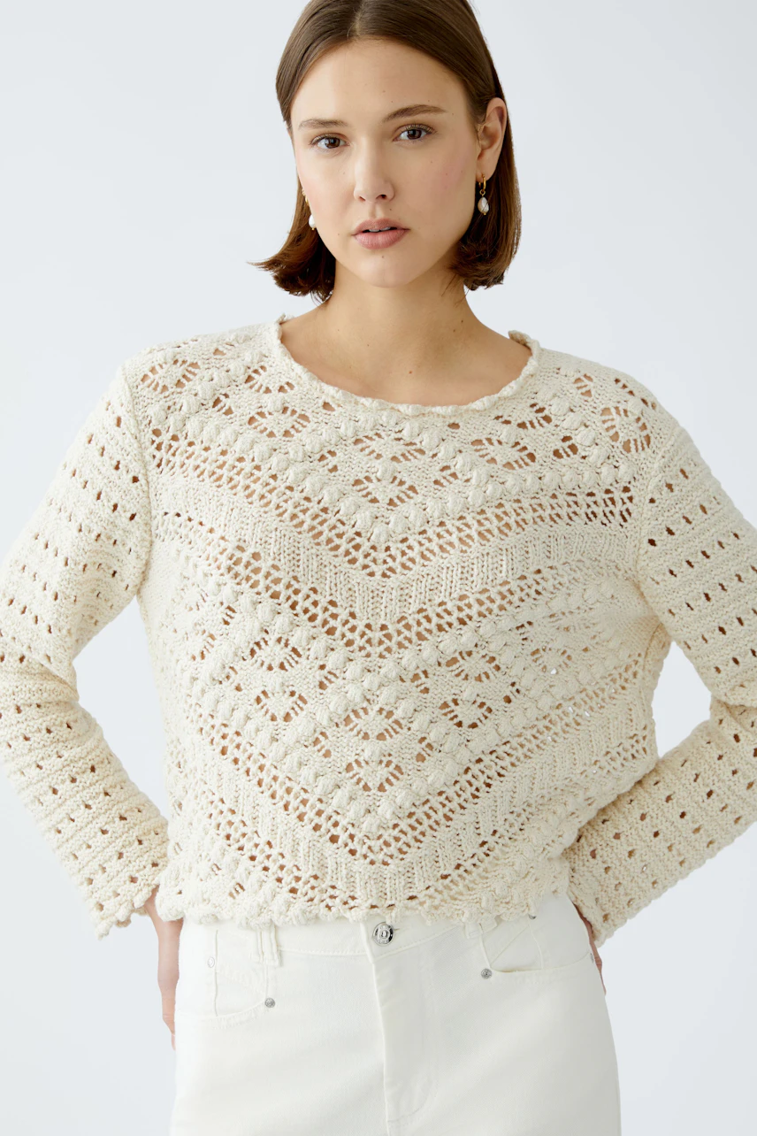 Stylish women's pullover: A woman in a cream knitted pullover with intricate patterns.