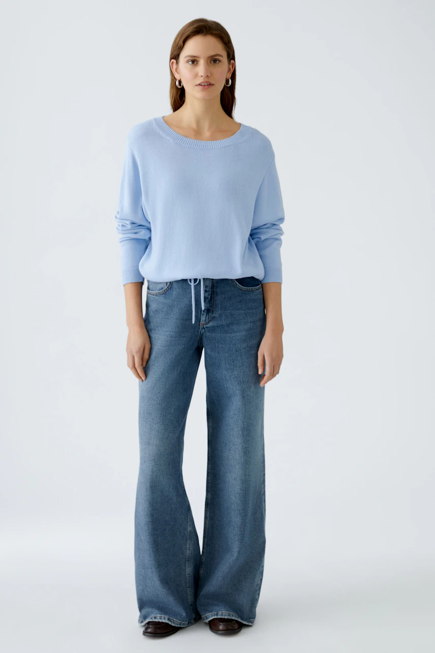 Damen-Pullover: Frau in hellblauem, lässigem Strickpullover mit weiten Jeans.