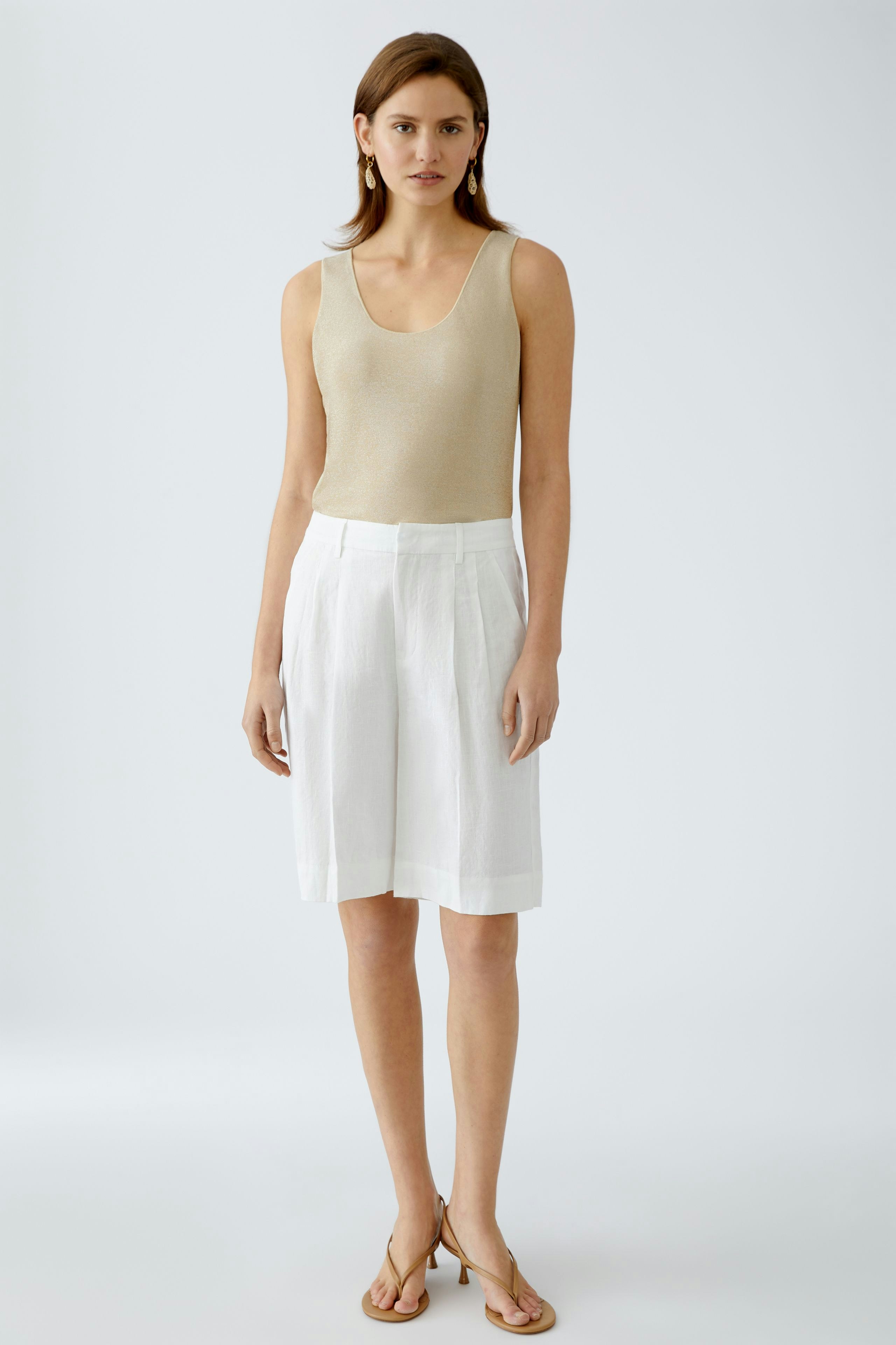 Stylish tank top: A woman in a beige tank top paired with white shorts, exuding effortless summer elegance.
