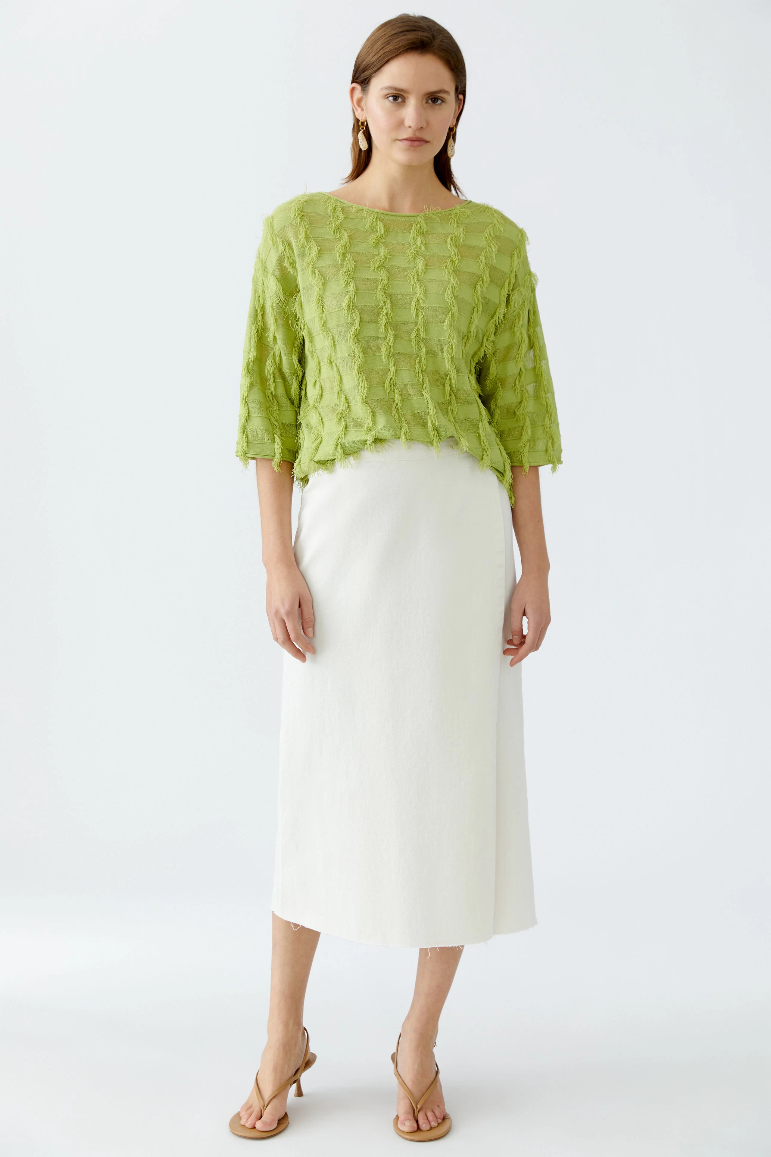 Damen-Pullover: Frau in grünem, strukturiertem Pullover mit lässigem Schnitt und weißem Rock.