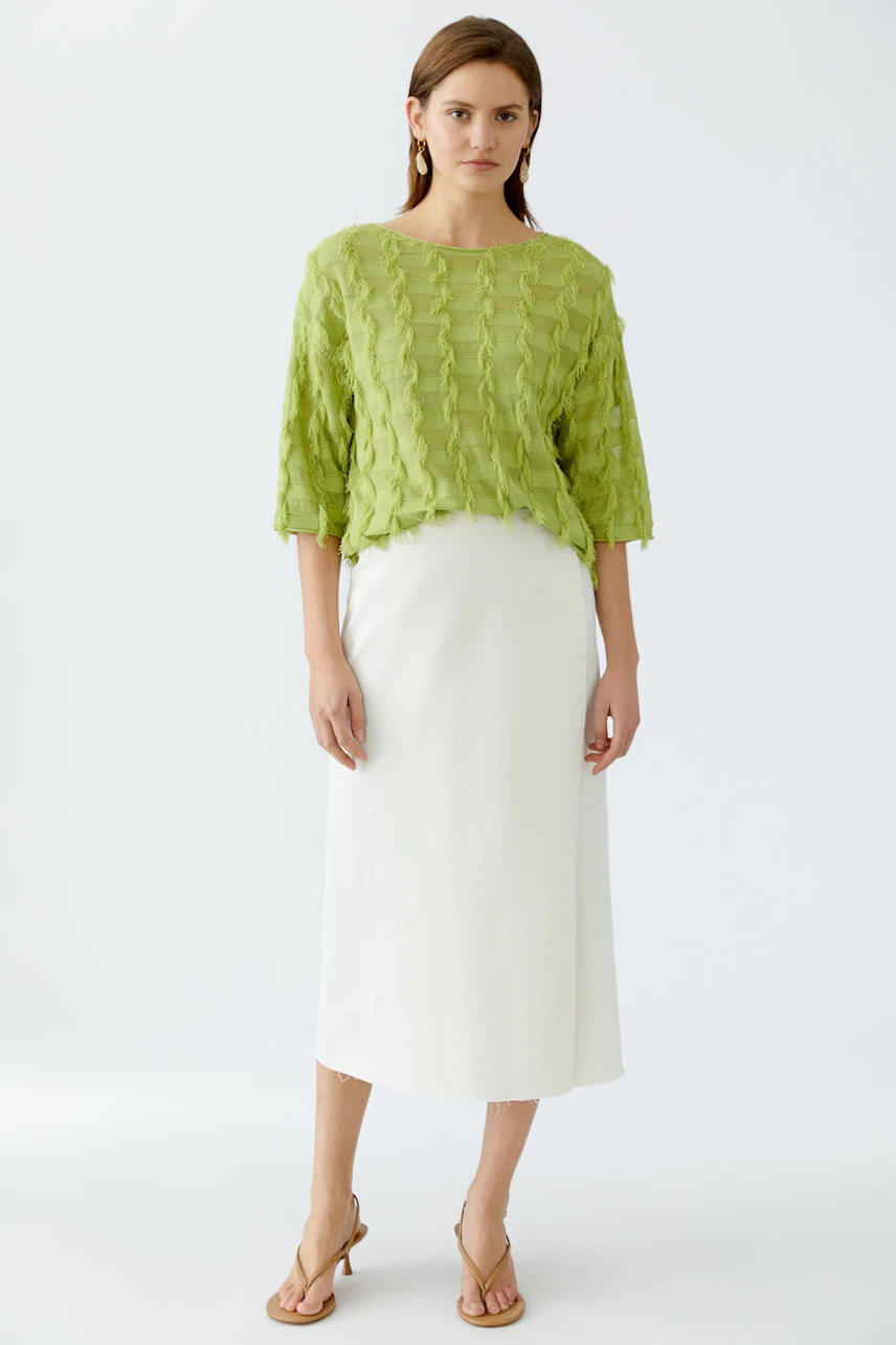 Damen-Pullover: Frau in grünem, strukturiertem Pullover mit lässigem Schnitt und weißem Rock.