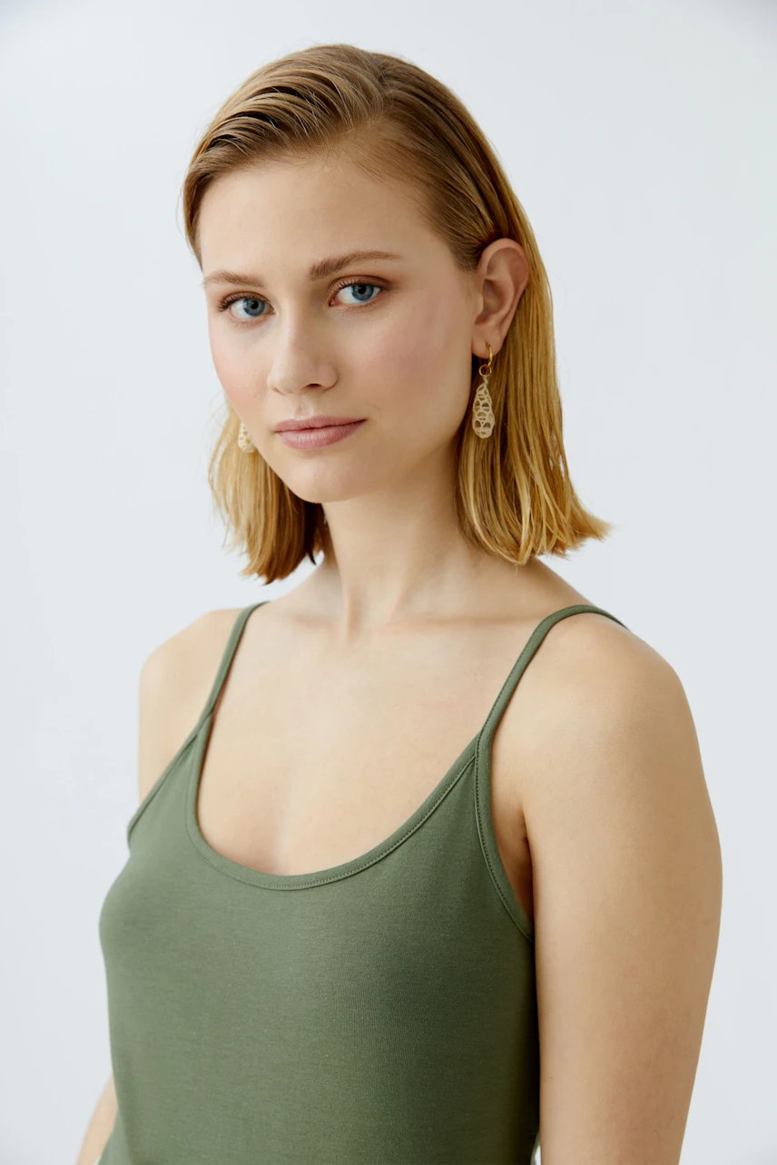 Stylish women's top: A woman in a green tank top, showcasing a simple and elegant design.