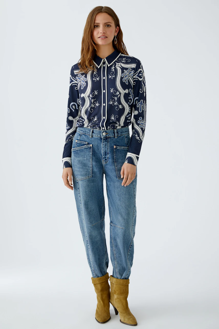 Stylish women's blouse: A woman in a navy patterned blouse paired with relaxed-fit jeans.