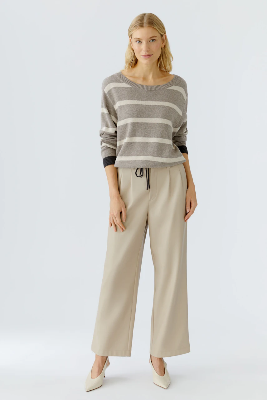 Damen-Pullover: Frau in gestreiftem Pullover mit lässigen Hosen und eleganten Schuhen.