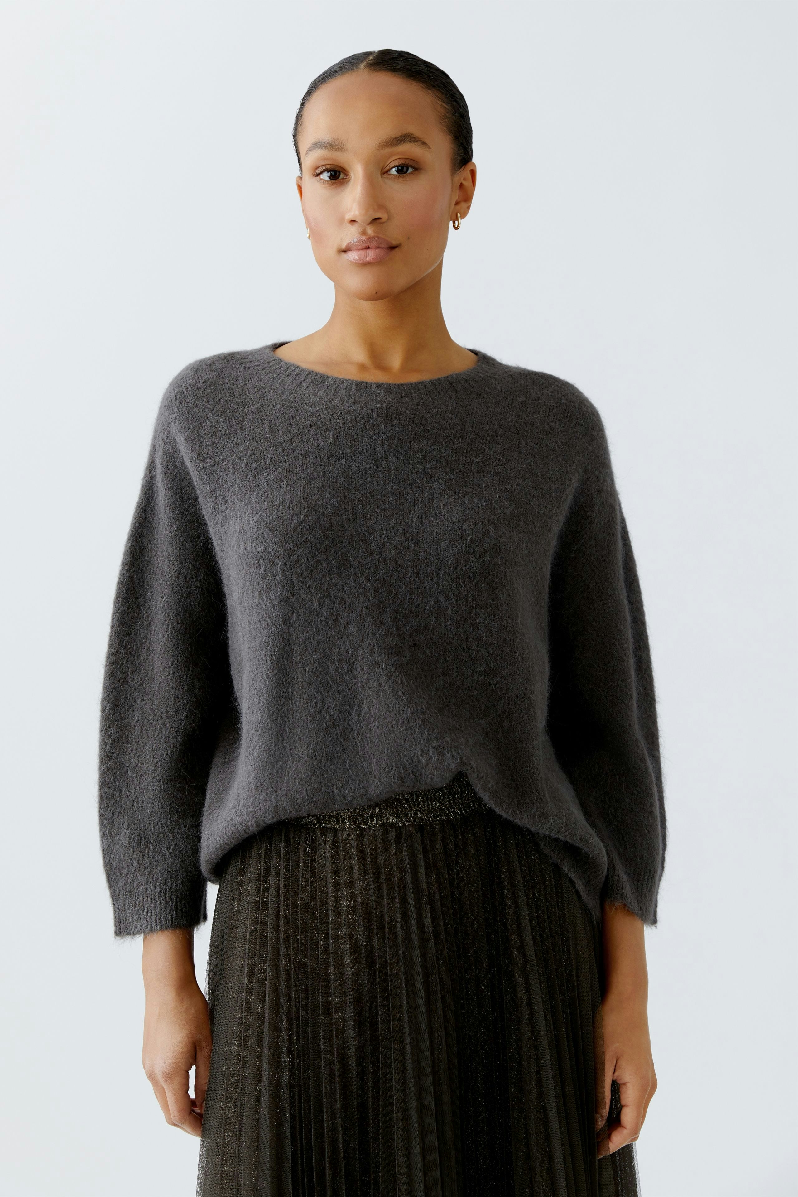 Casual women's pullover: A woman in a soft gray pullover paired with a pleated skirt.