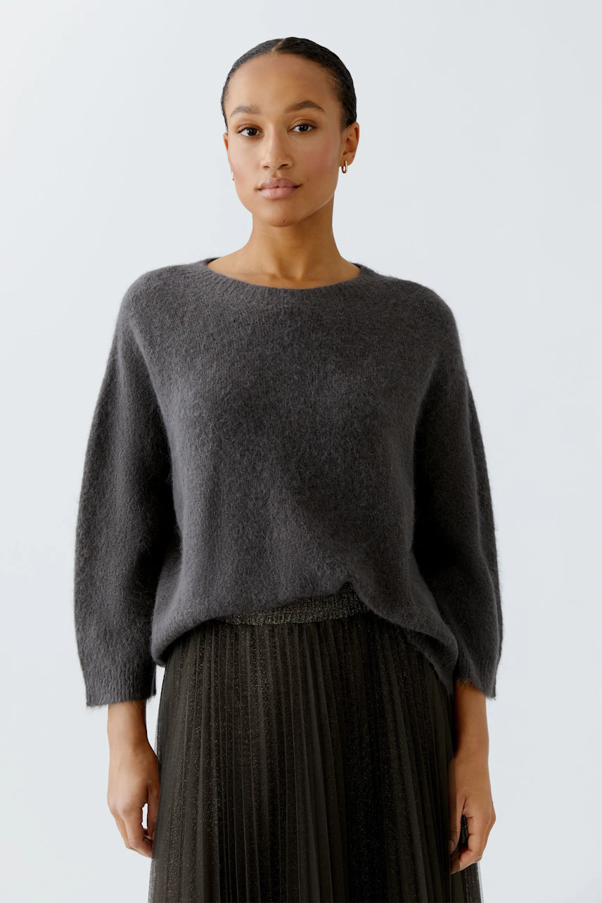 Casual women's pullover: A woman in a soft gray pullover paired with a pleated skirt.