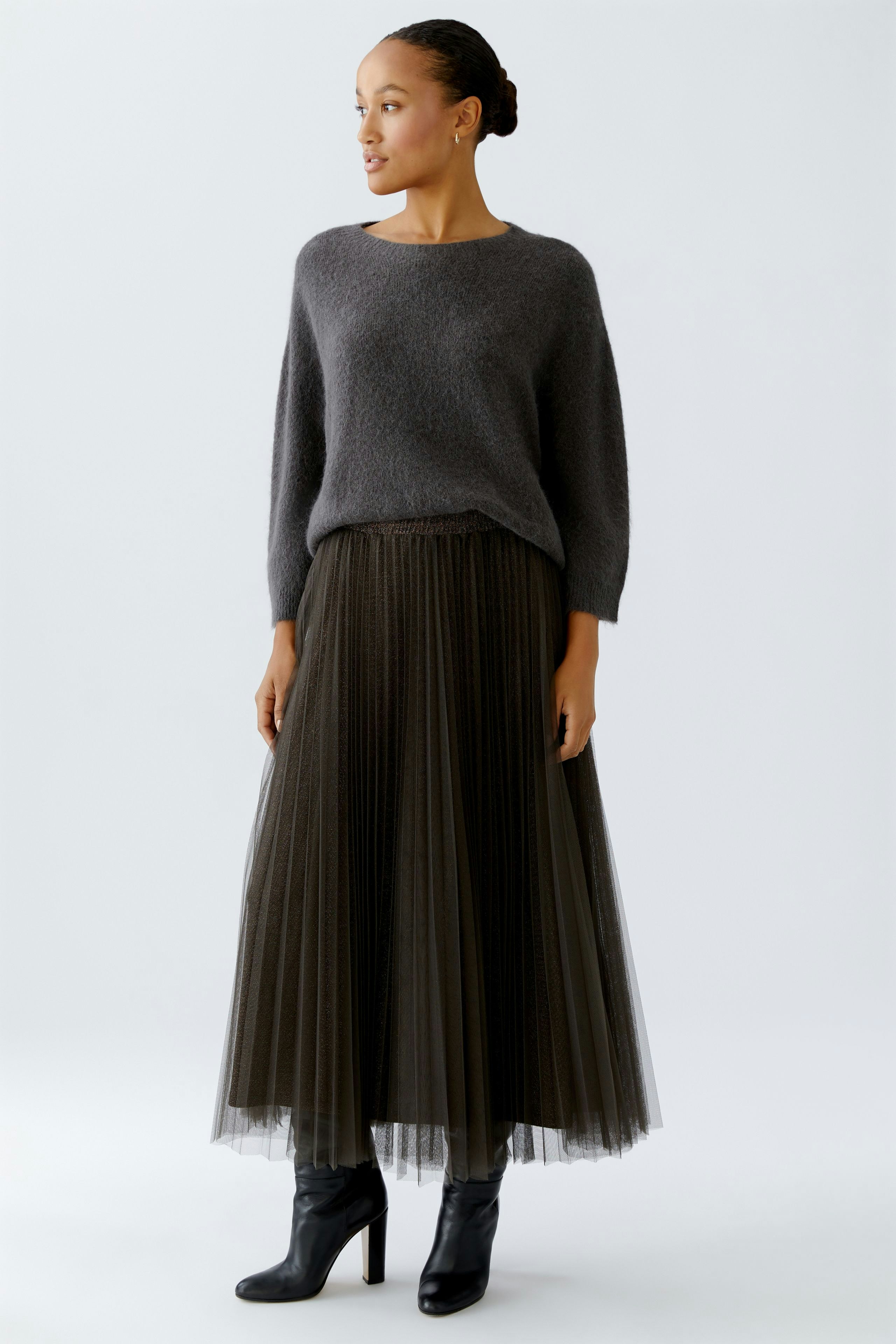 Casual women's pullover: Woman in a cozy gray pullover paired with a flowy skirt, exuding relaxed style.