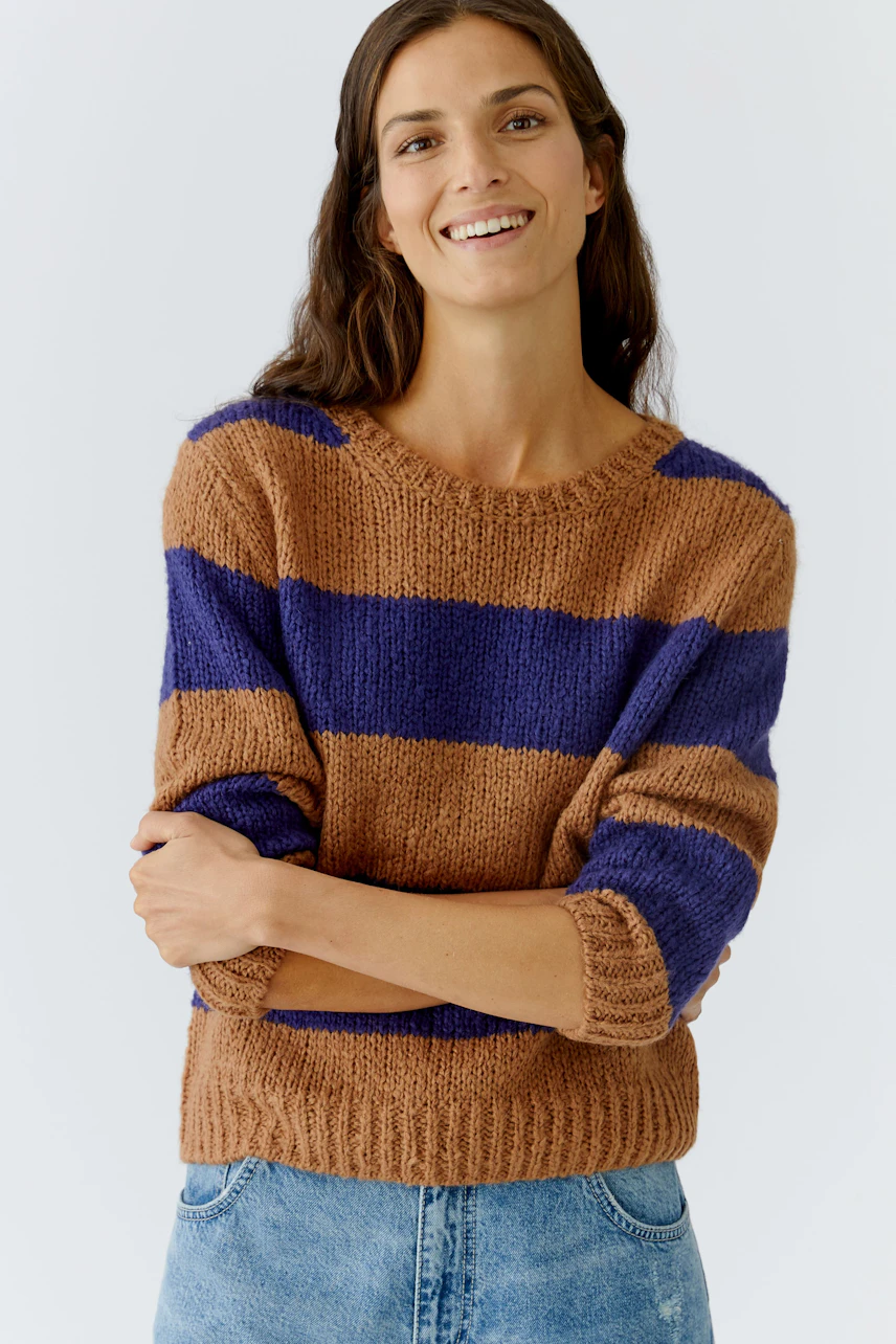Casual women's pullover: Smiling woman in a brown and purple striped pullover with relaxed fit.