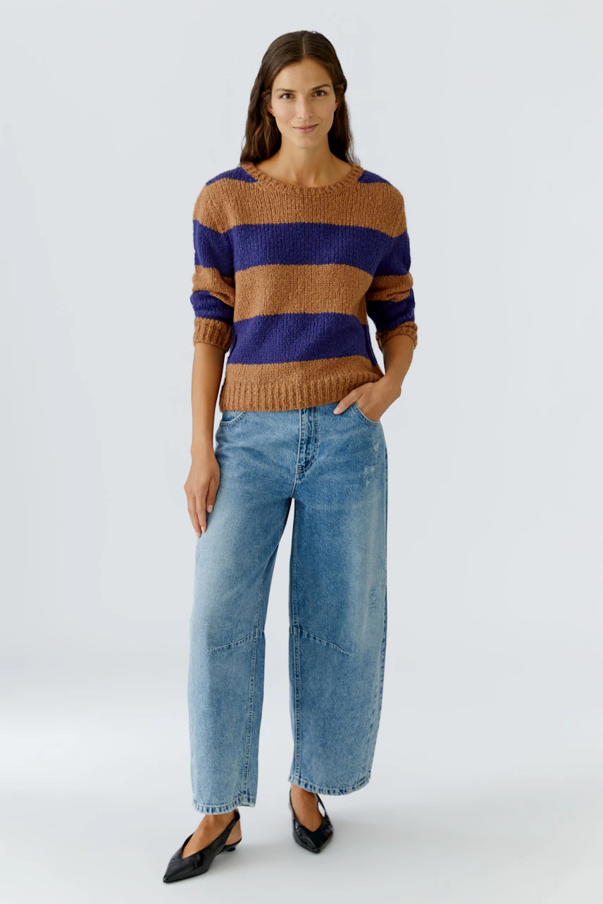Casual women's pullover: A woman in a striped pullover with brown and purple hues, paired with relaxed jeans.