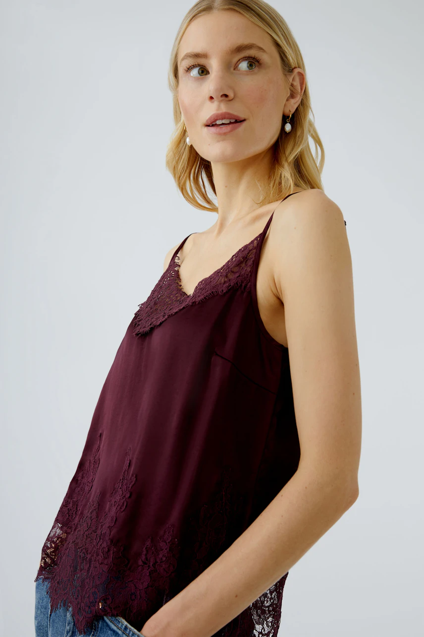 Damen-Top: Junge Frau in einem burgunderfarbenen Top mit Spitze, lässig und modern.